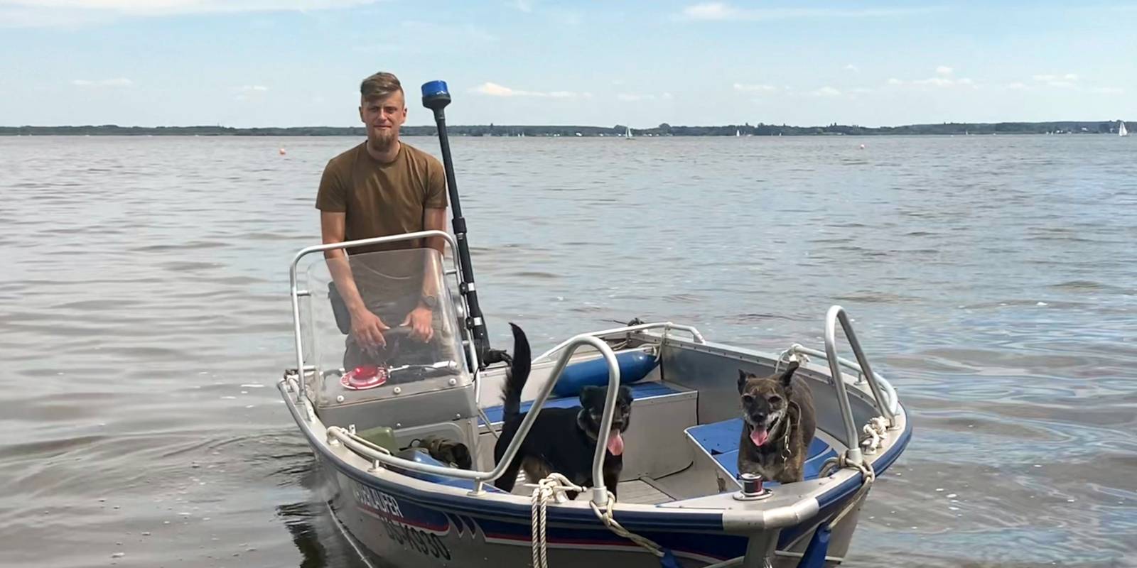 Ein Mann fährt in einem Motorboot über das Steinhuder Meer. es sind auch zwei Hunde an Bord.
