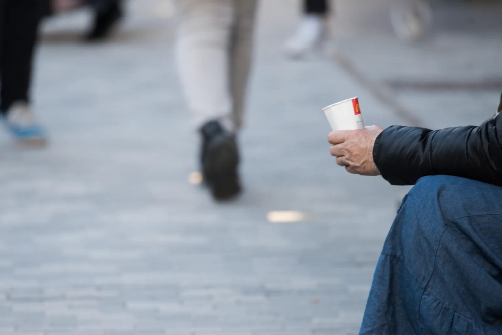 Obdachloser bettelt auf einer belebten Einkaufsstraße