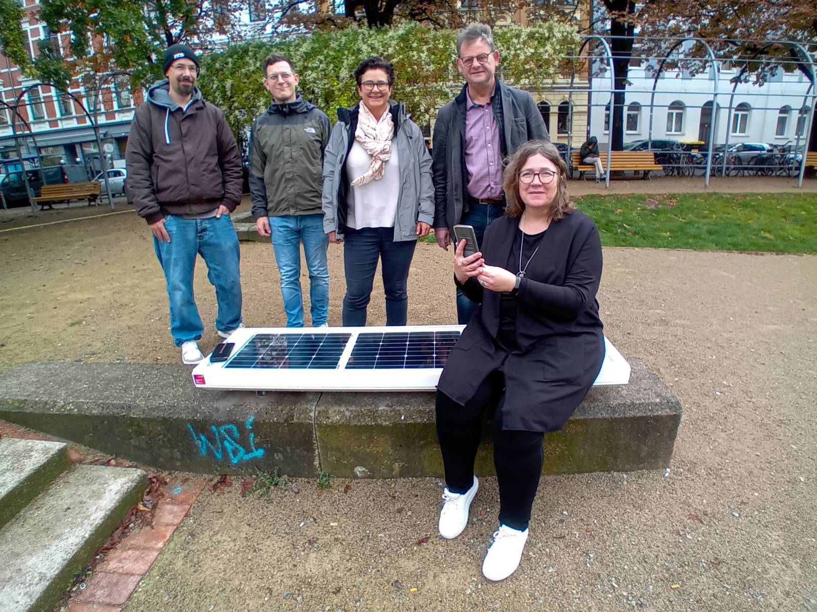 Fünf Personen rund um eine Bank.