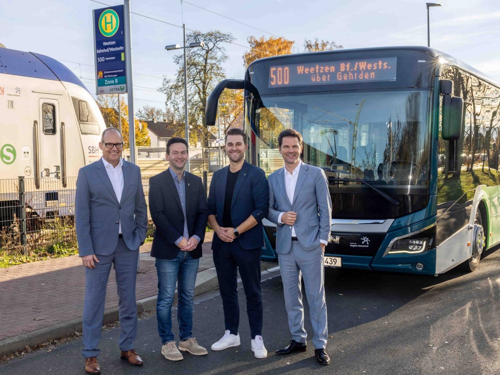 Vier Männer vor einem Bus der Linie 500 am Bahnhof Weetzen.