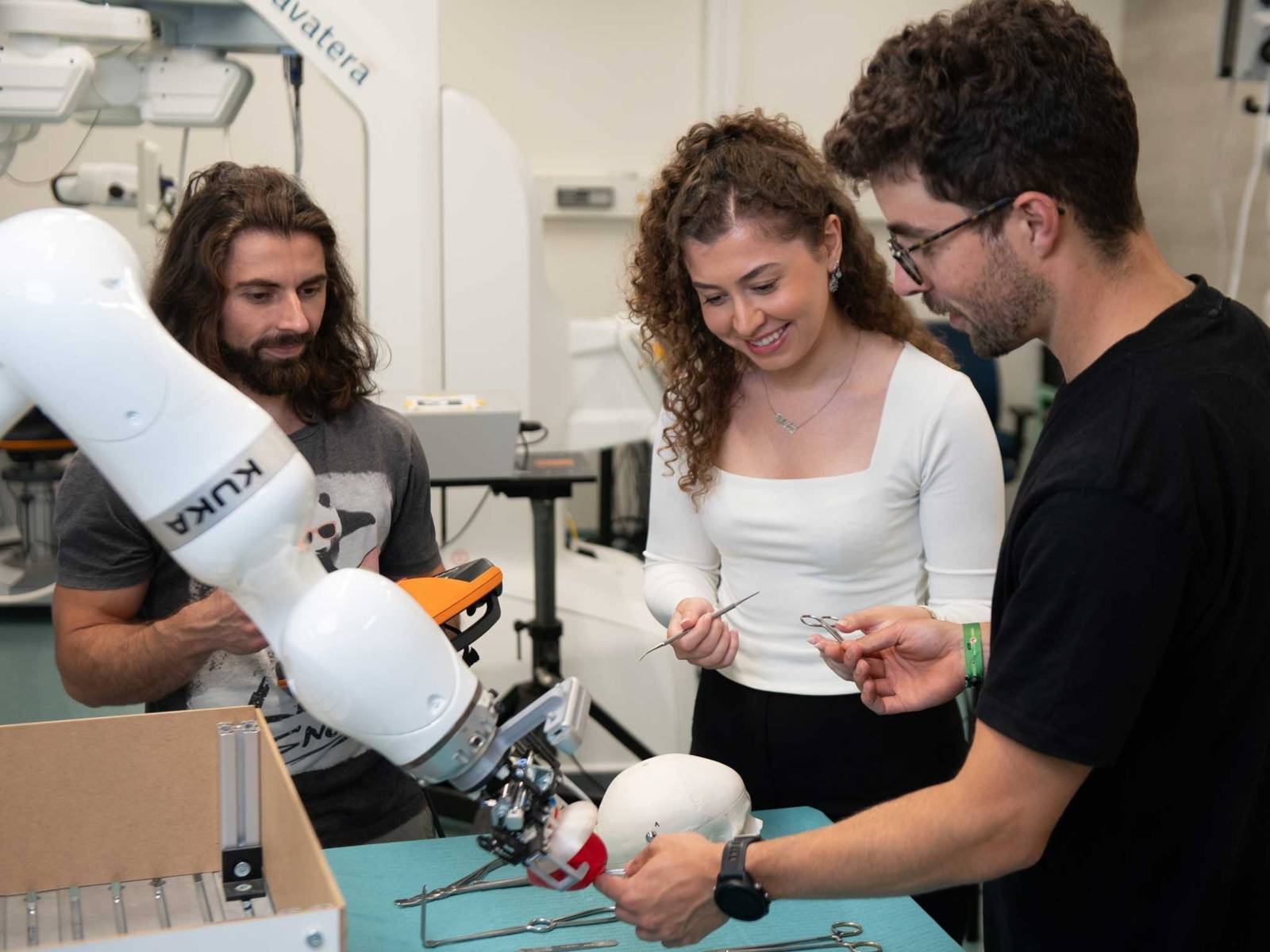 Zwei Männer und eine Frau mit Roboterarm.