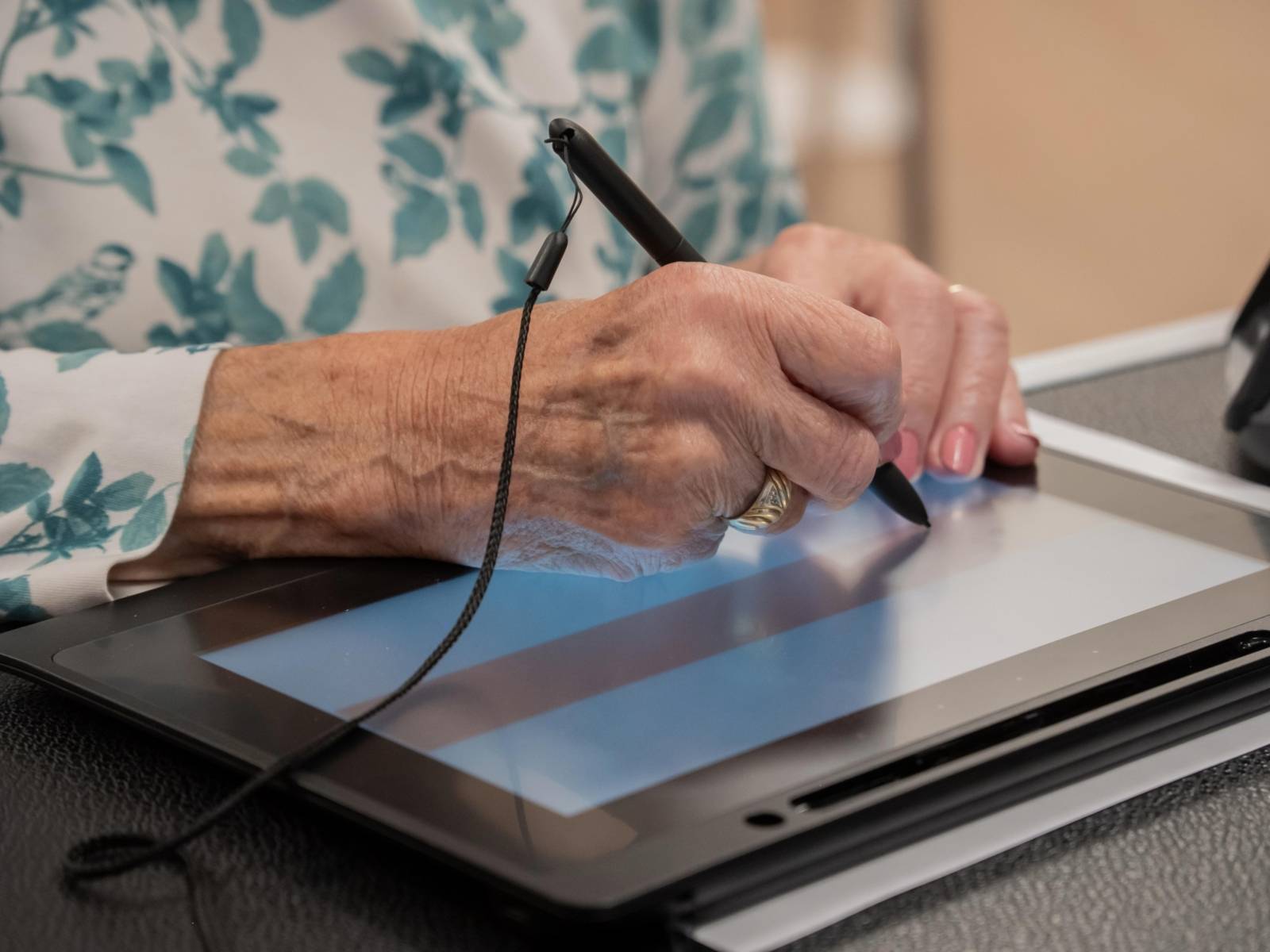 Eine Person unterschreibt mit einem Stylus auf einem Tablet.