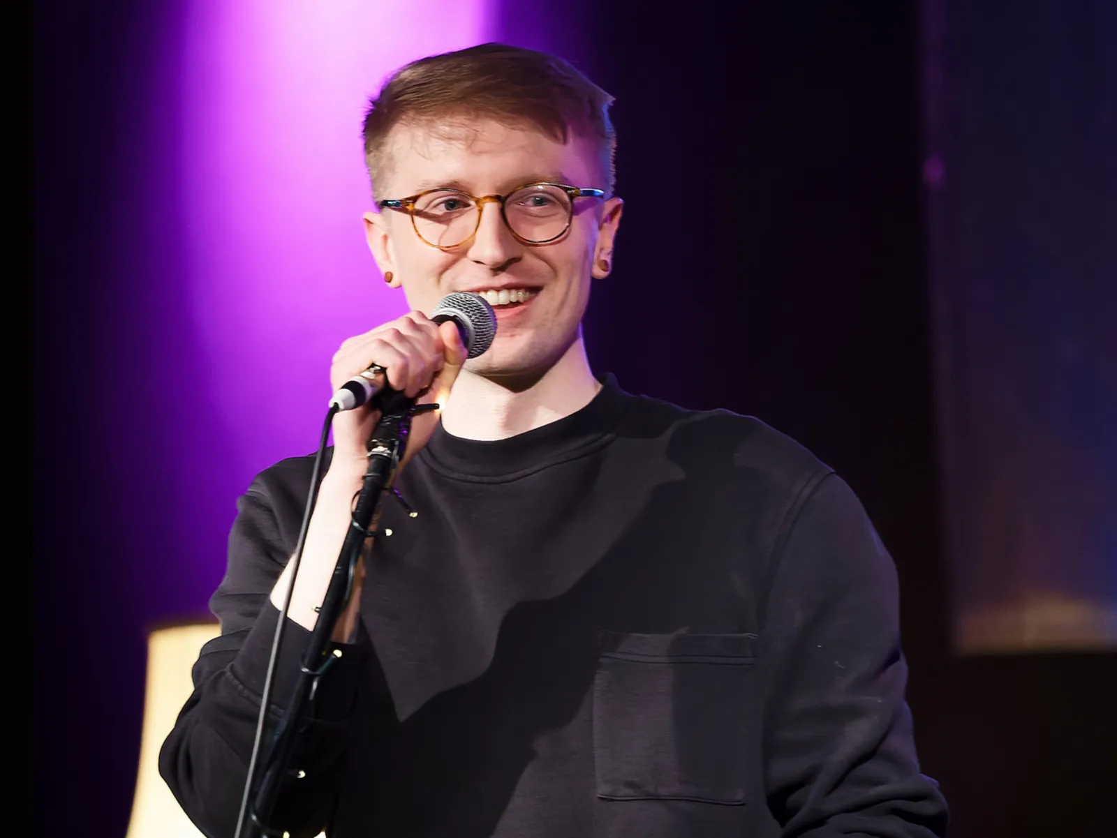 Ein junger Mann spricht in ein Standmikrofon