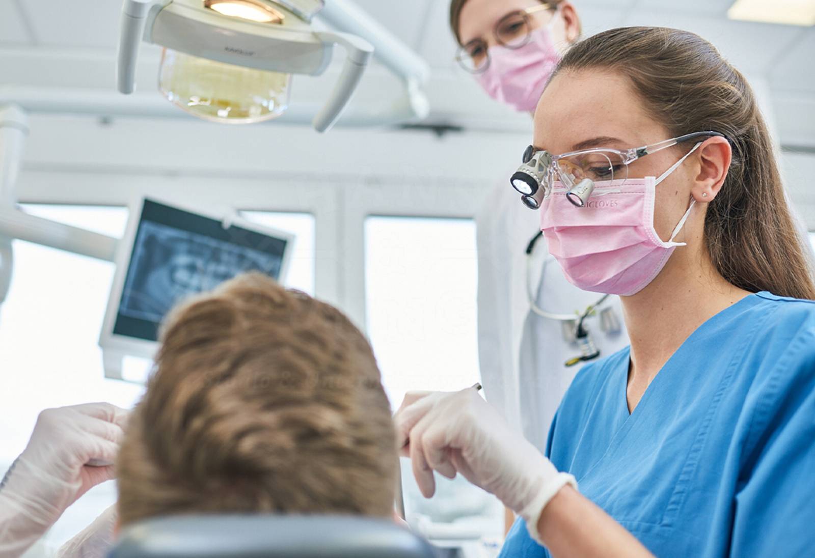 Eine Zahnmedizin-Studentin untersucht den Zahnstand eines Patienten