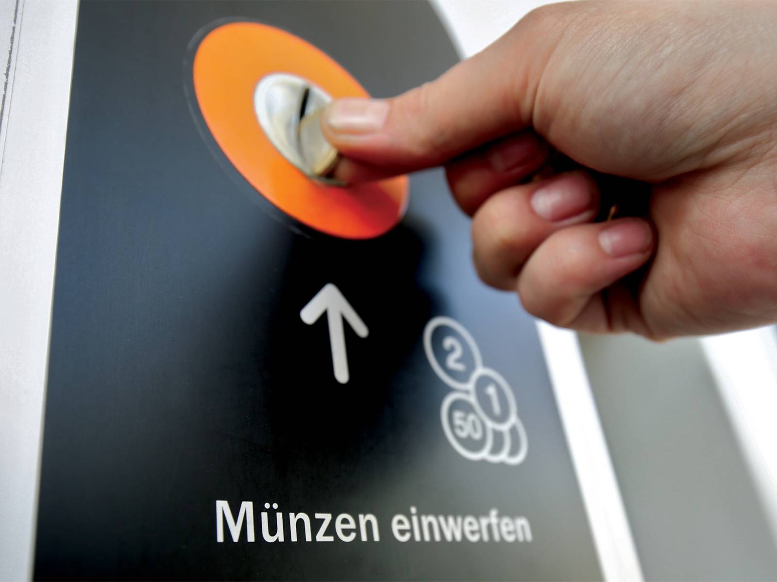 Die Barzahlung an einem Fahrkartenautomat mit Fokus auf den Münzeinwurf samt Beschriftung "Münzen einwerfen".