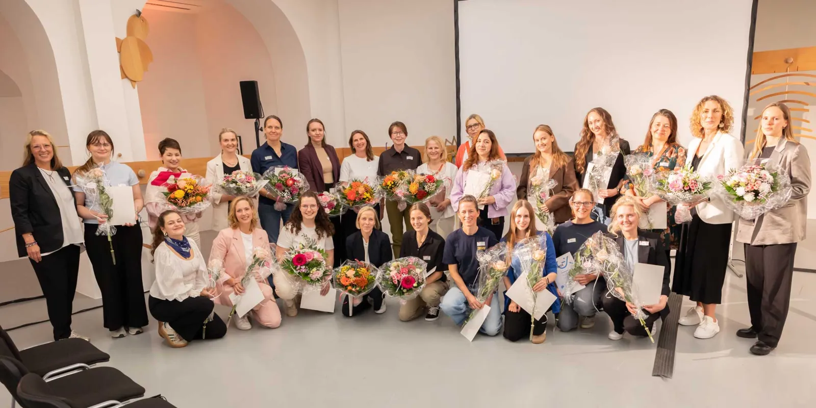 Frauen mit Blumenstr&auml;u&szlig;en in den H&auml;nden posieren vor der Kamera.
