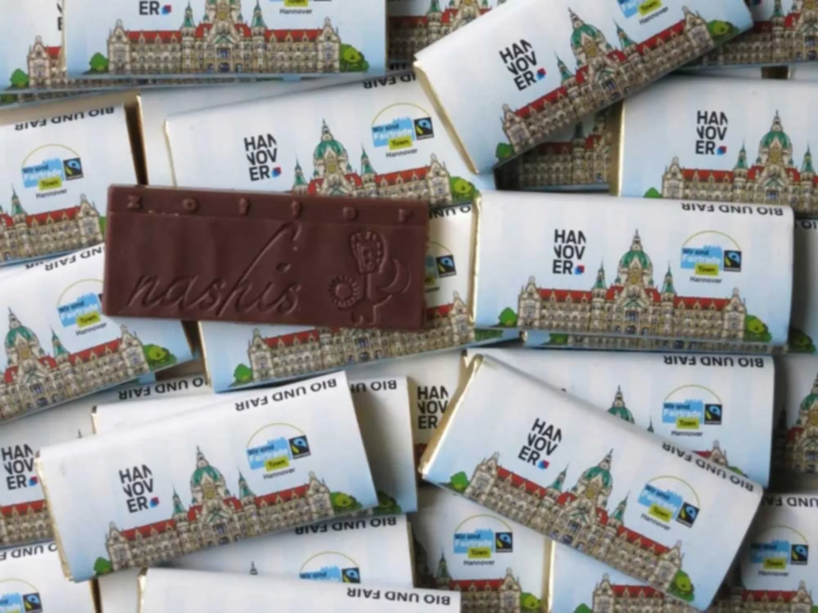 Kleine Schokoladentäfelchen, deren Verpackung mit dem Rathausbild Hannovers und dem Fair-Trade-Siegel versehen ist.