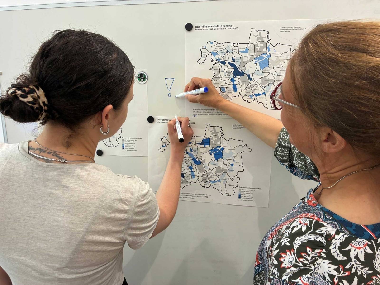 Zwei Frauen zeichnen etwas auf Karten an einem Flipchart ein.