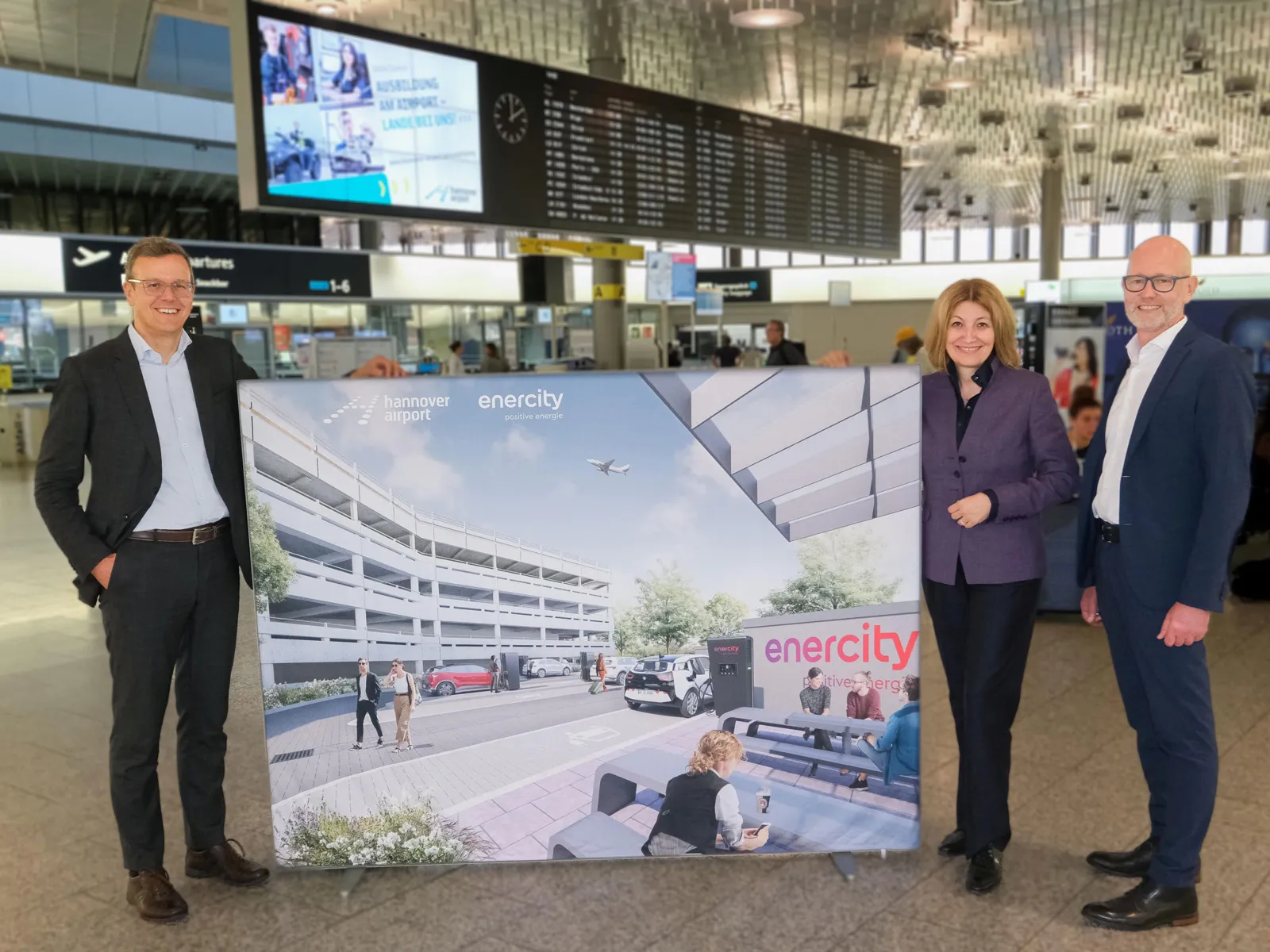 Eine Frau und zwei Männer halten ein sehr großes Plakat.