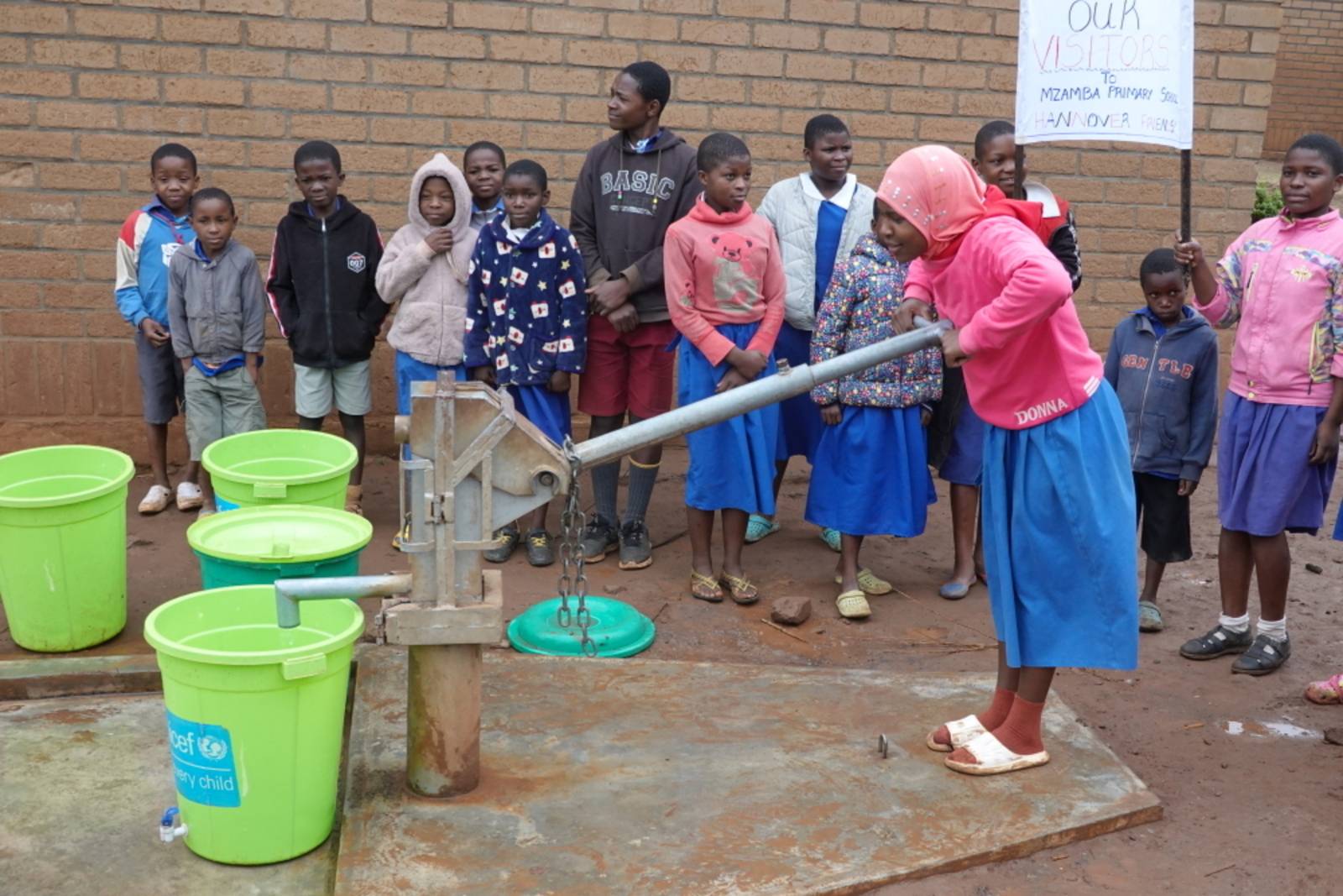 Eine Schülerin pumpt Wasser aus dem neuen Brunnen in der Mzamba Primary School.
