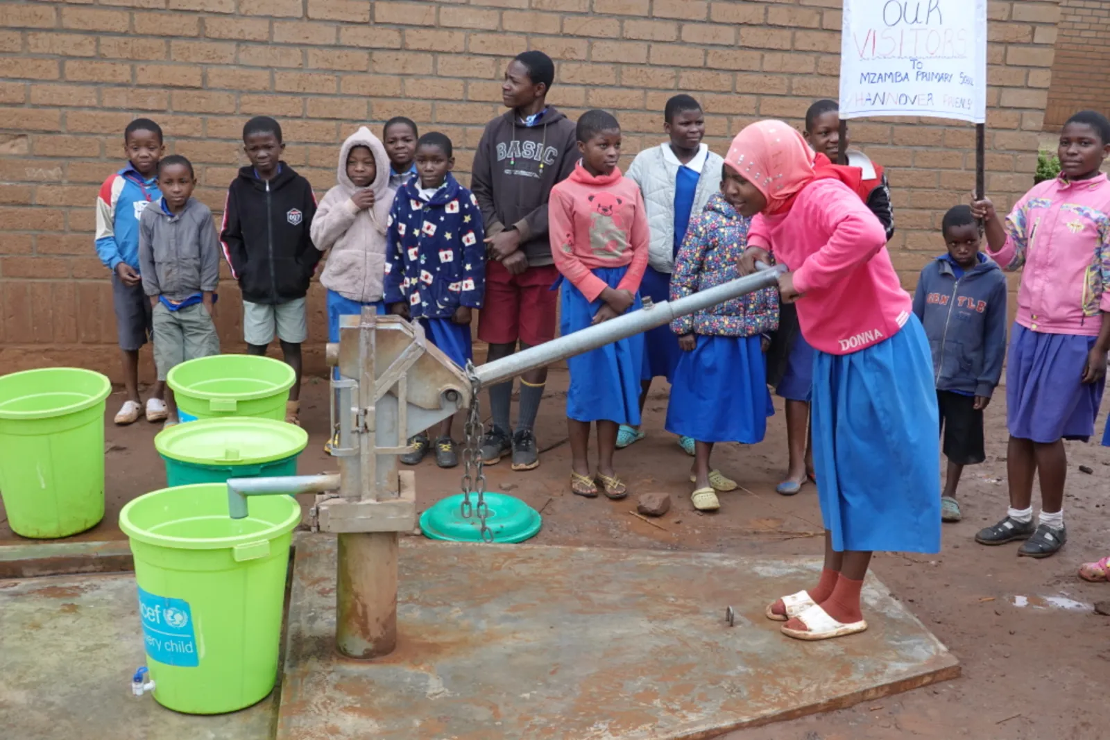 Eine Sch&uuml;lerin pumpt Wasser aus dem neuen Brunnen in der Mzamba Primary School.