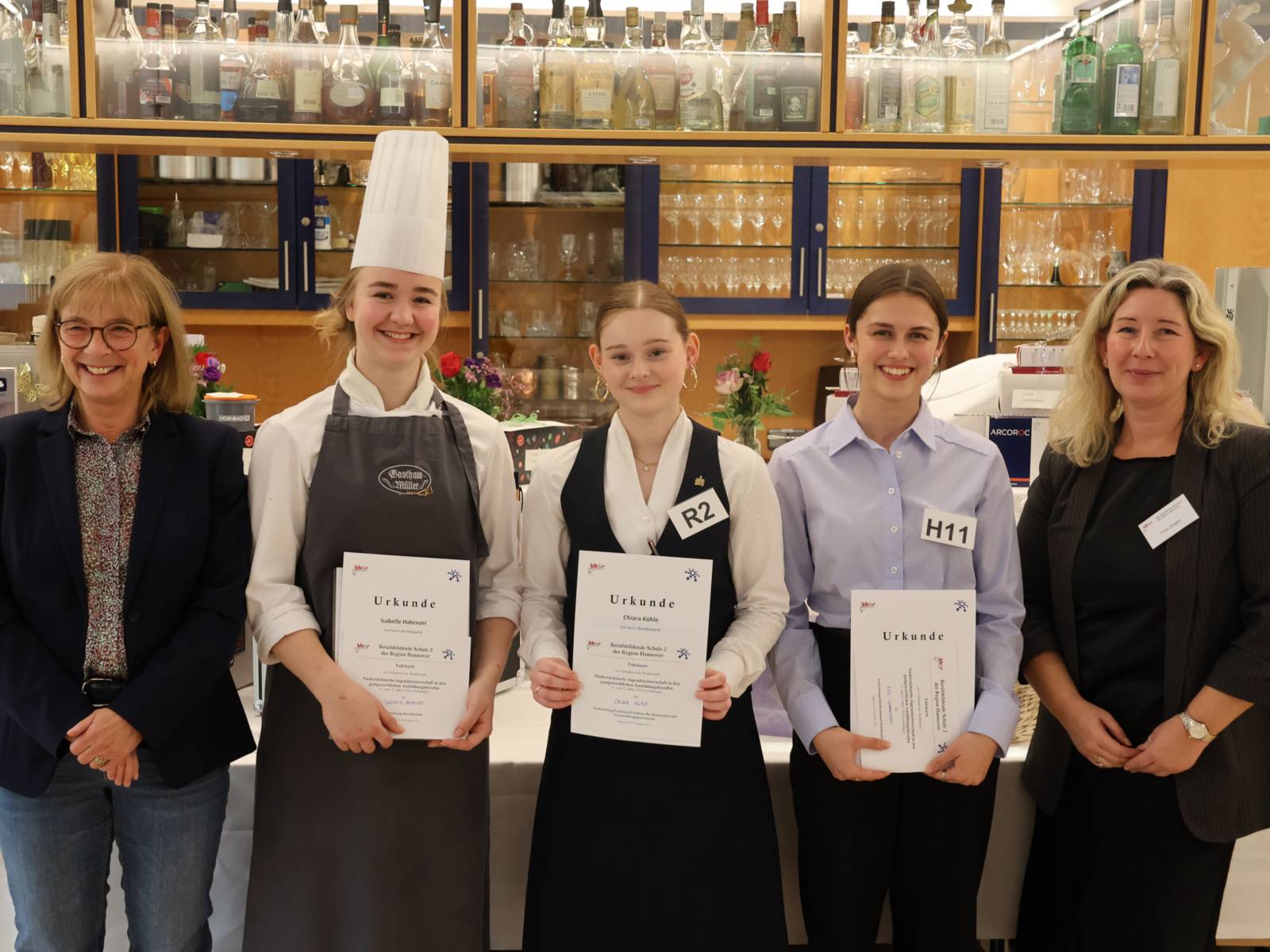 Fünf Personen, drei davon halten eine Urkunde in der Hand