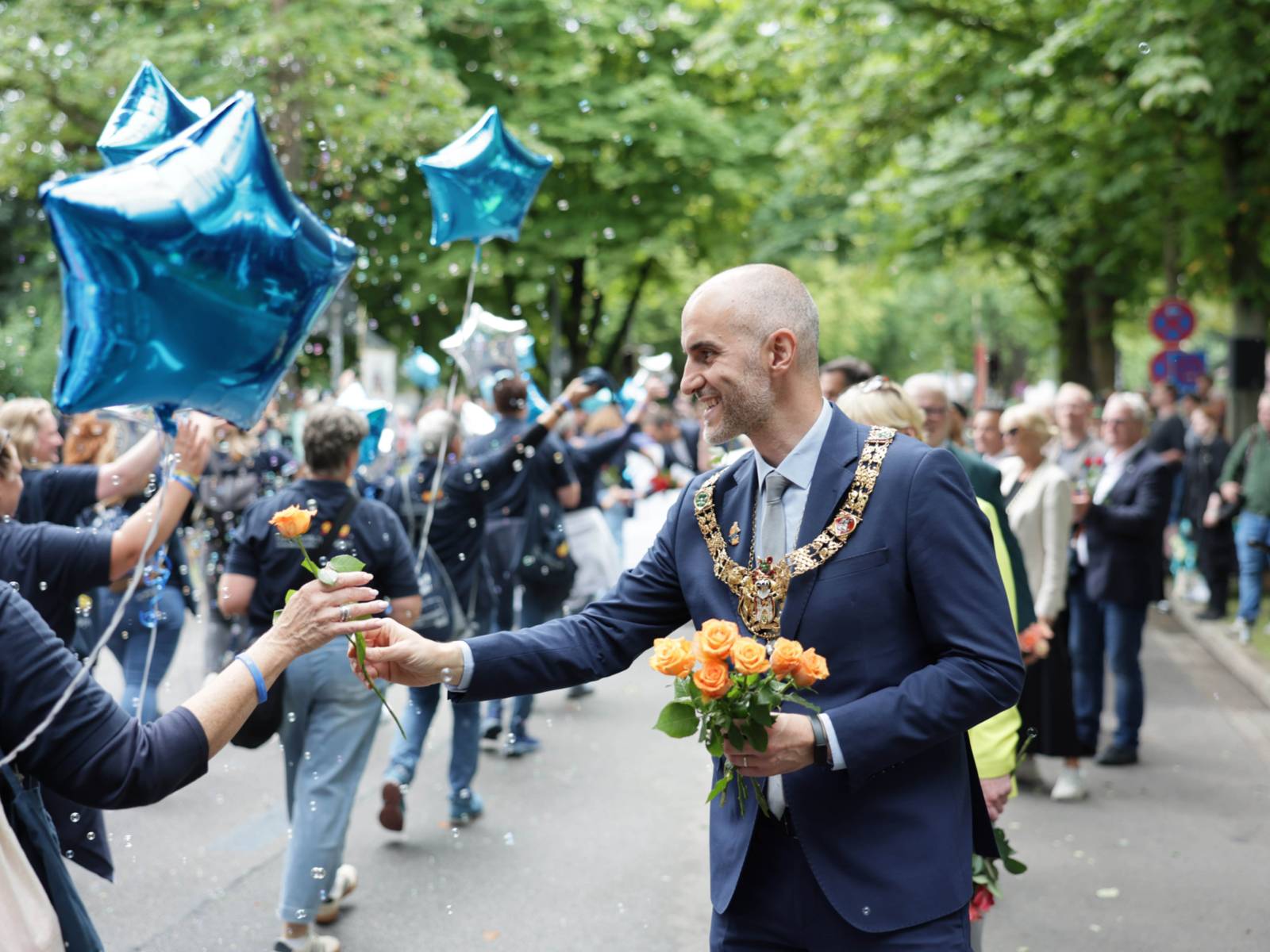 Ein Mann verteilt Blumen an die Menschen beim Festzumzug.