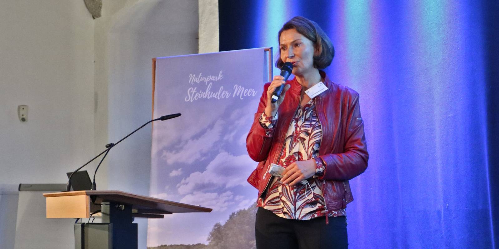 Eine Frau steht auf einer Bühne und hält ein Mikrofon.