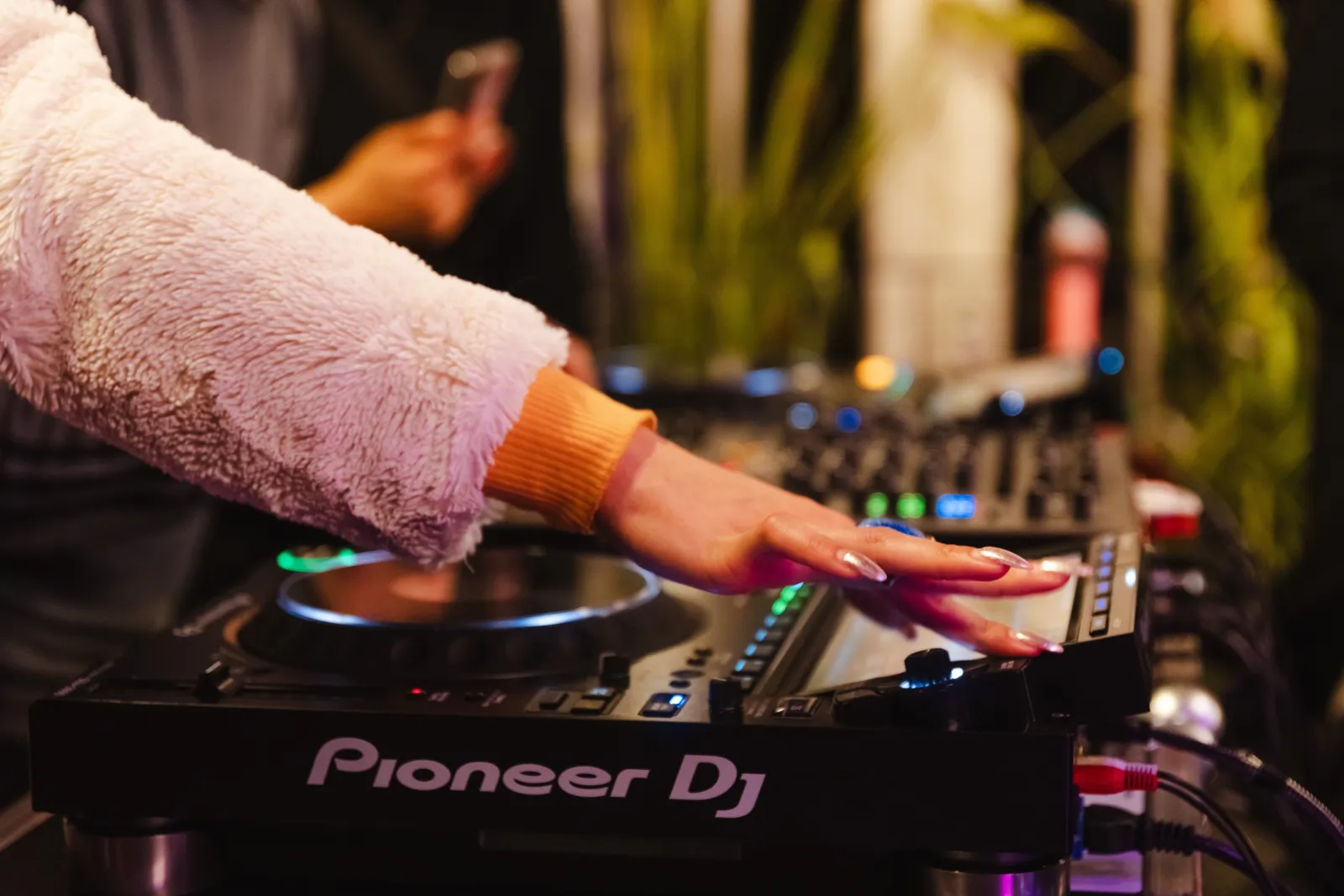 Ein DJ-Pult. Eine Hand mit langen Fingern&auml;geln bedient es.