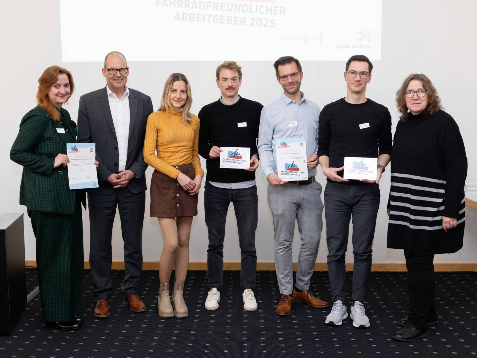 Sieben Personen, vier davon halten eine Auszeichnung in den Händen.