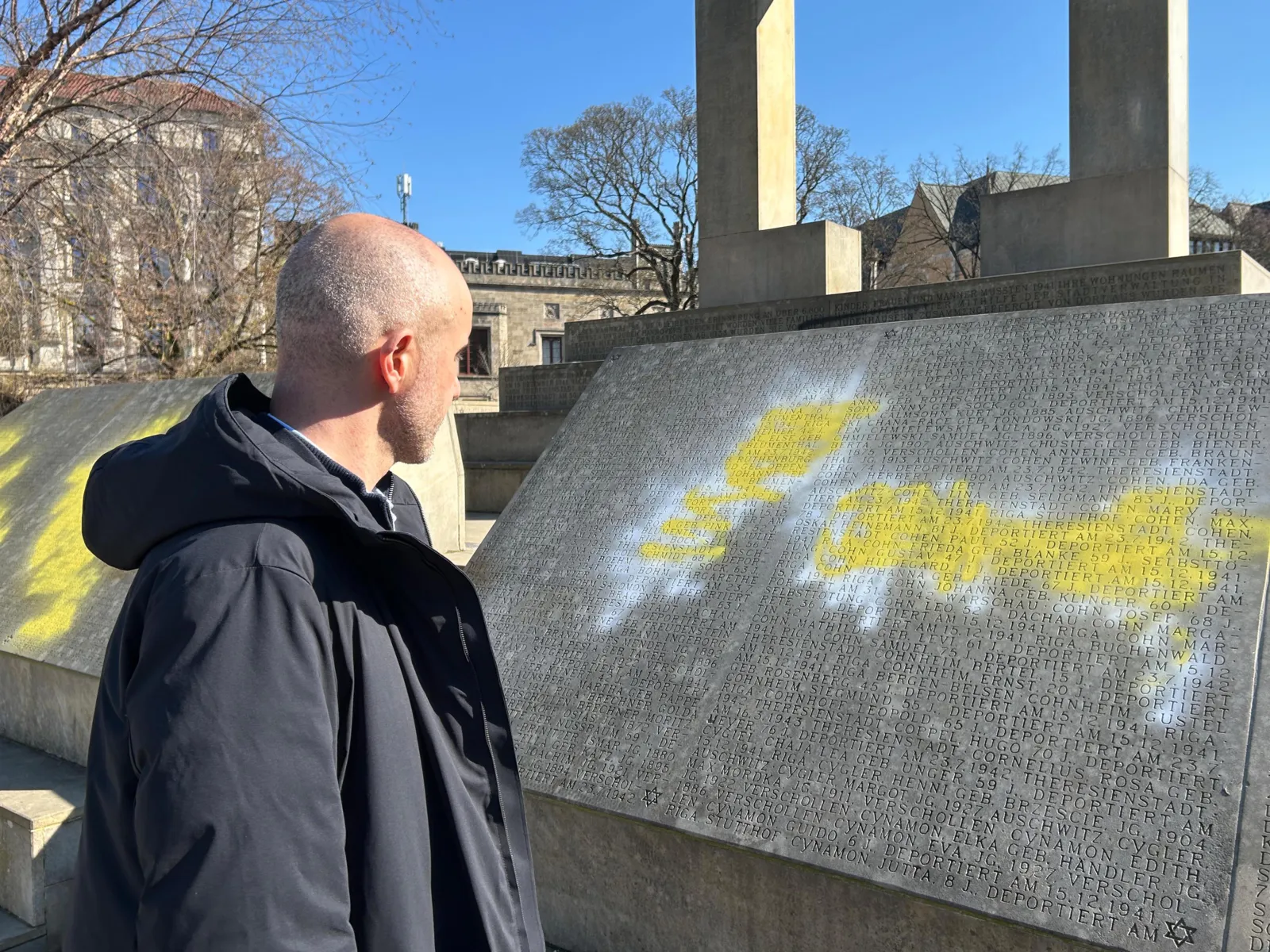 Ein beschmiertes Holocaustmahnmal. Davor der Oberbürgermeister.