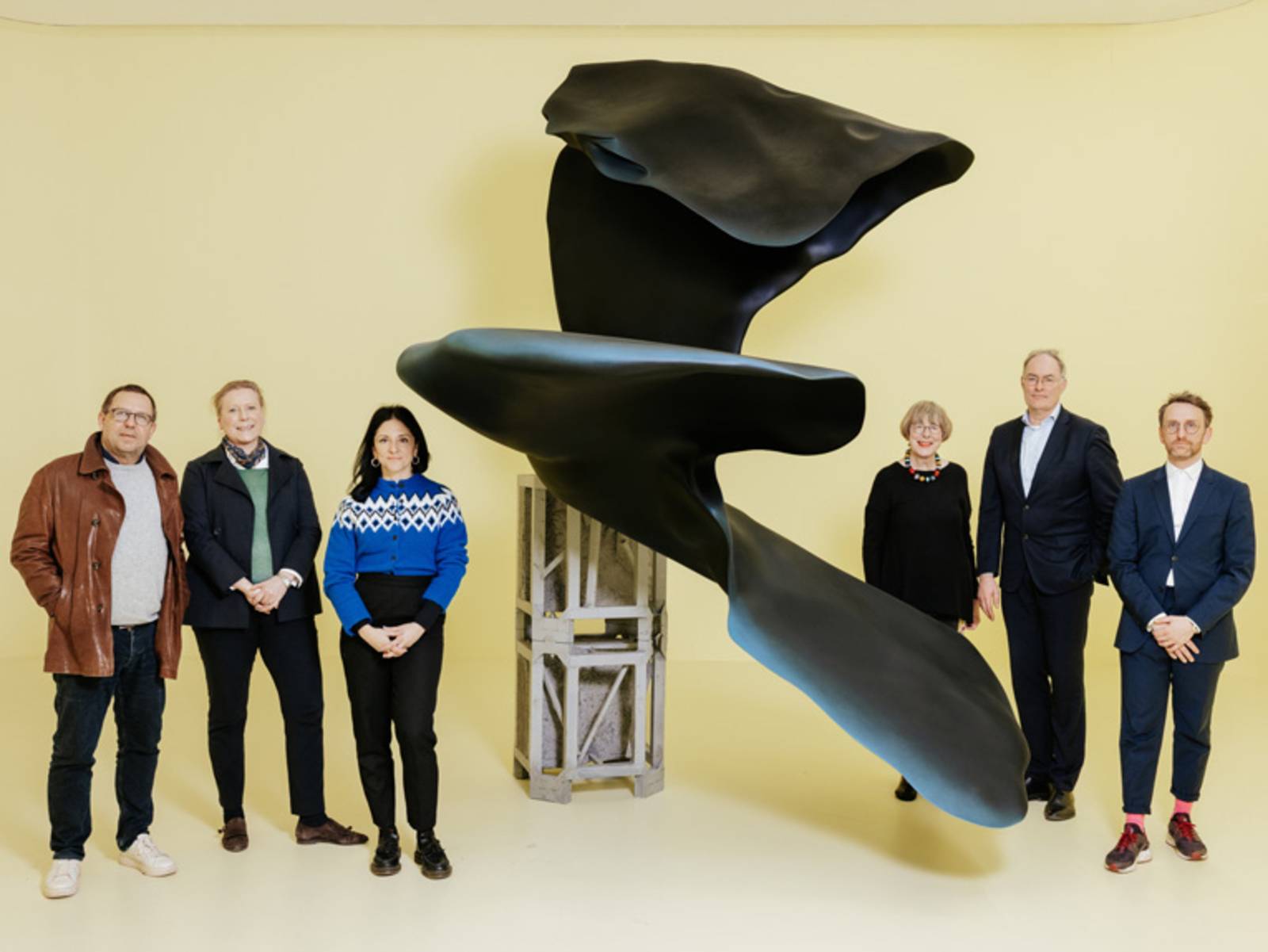 Sechs Personen stehen neben einer Skulptur
