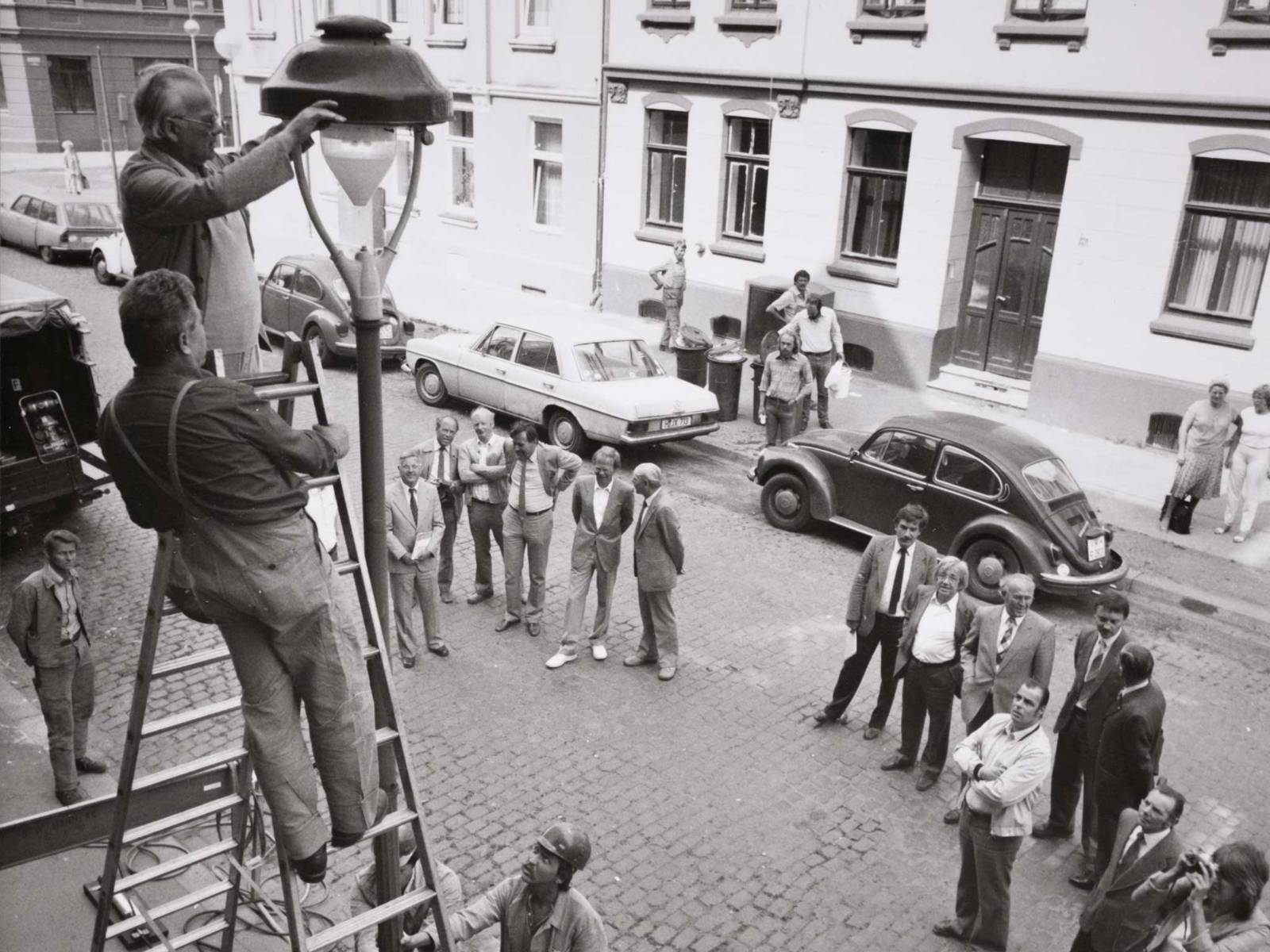 Arbeiter auf einer Leiter an einer Stra&szlig;enlaternen. Historische Schwarz-Wei&szlig;-Aufnahme