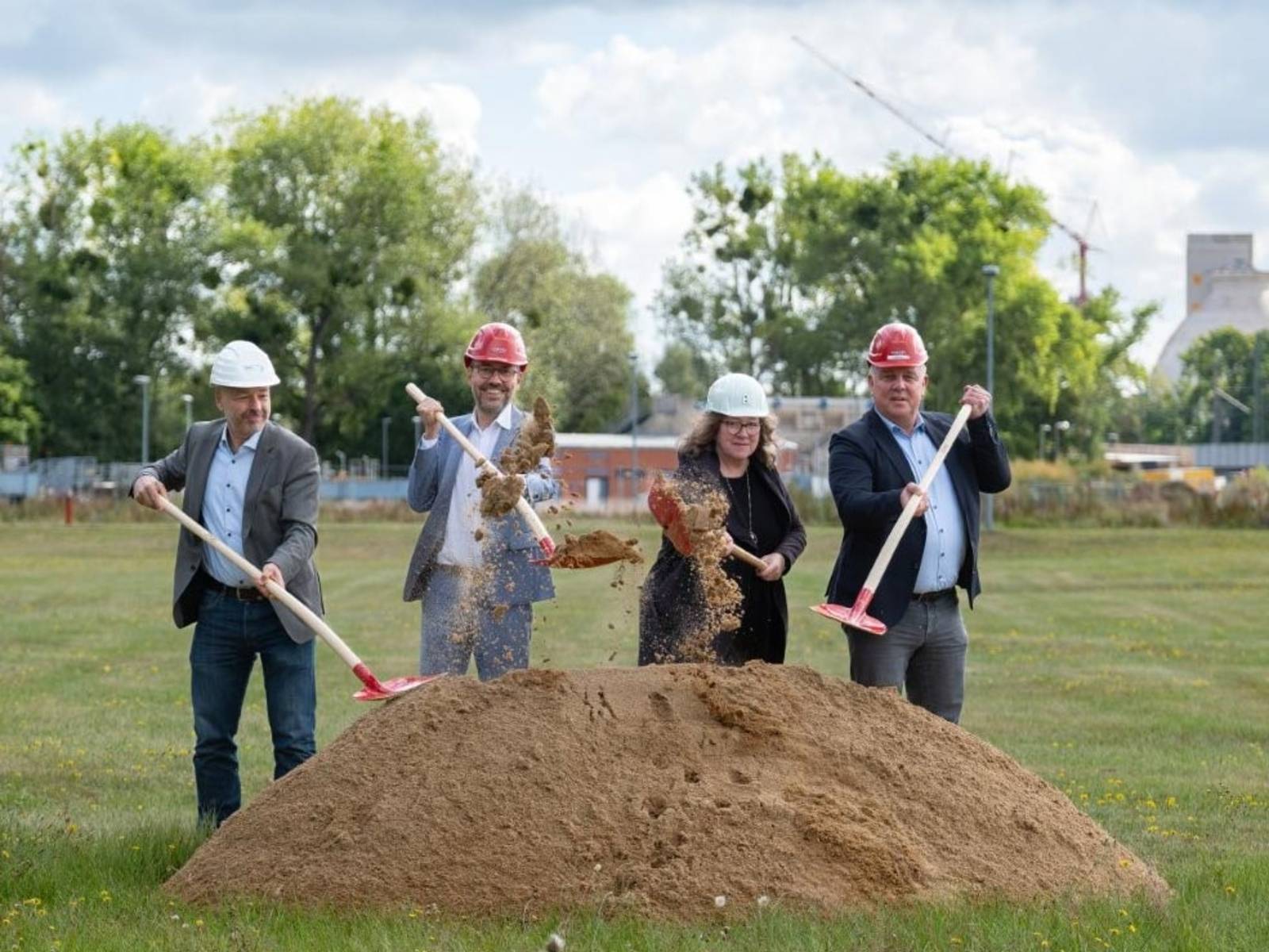 Vier Personen, die auf einer Wiese einen symbolischen Spatenstich vollziehen.