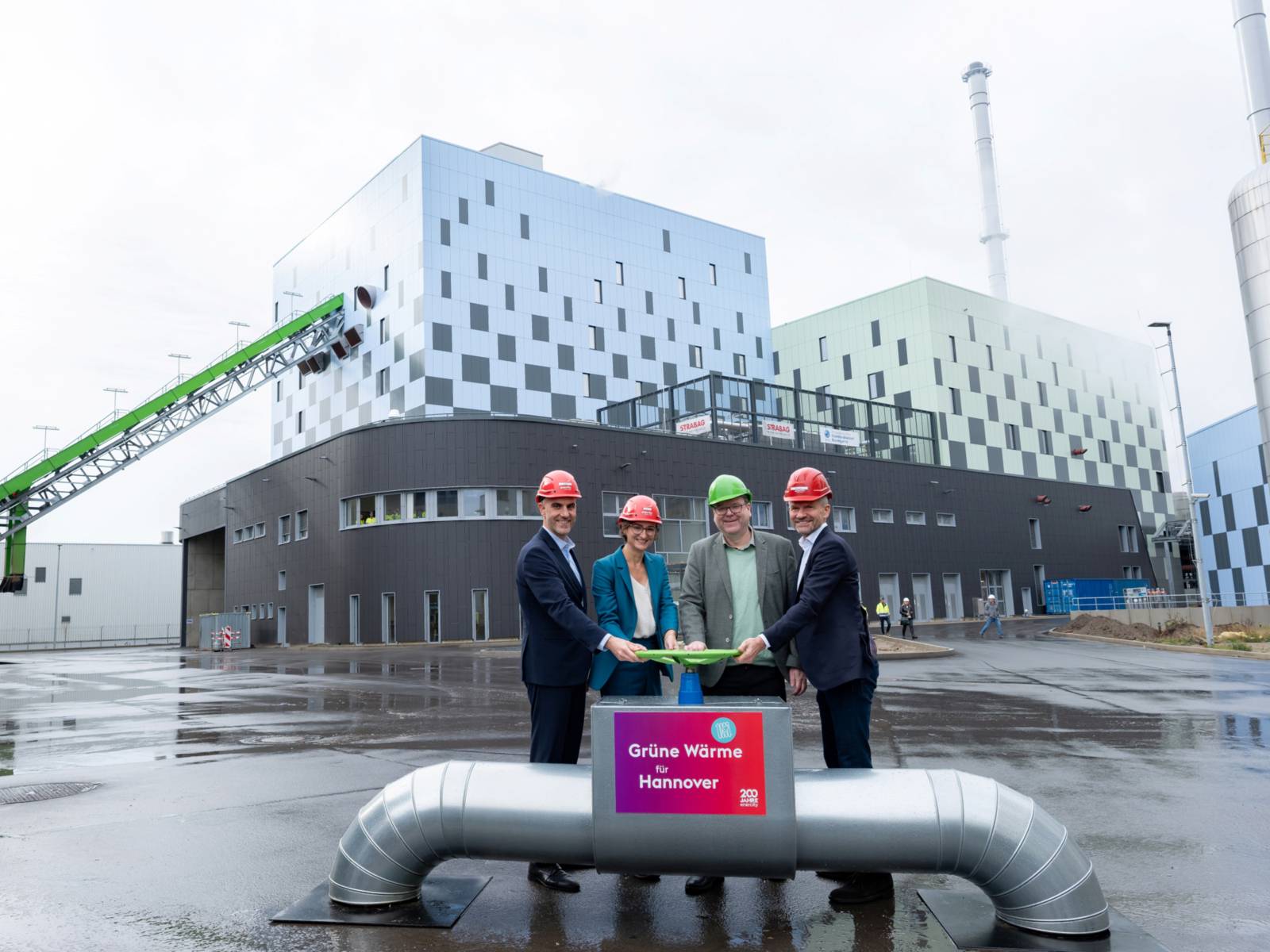 Bier Personen vor einem Biomasse-Heizkraftwerk.