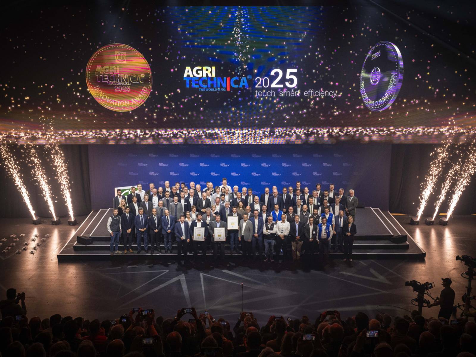 Menschen mit Urkunden auf einer B&uuml;hne vor Publikum