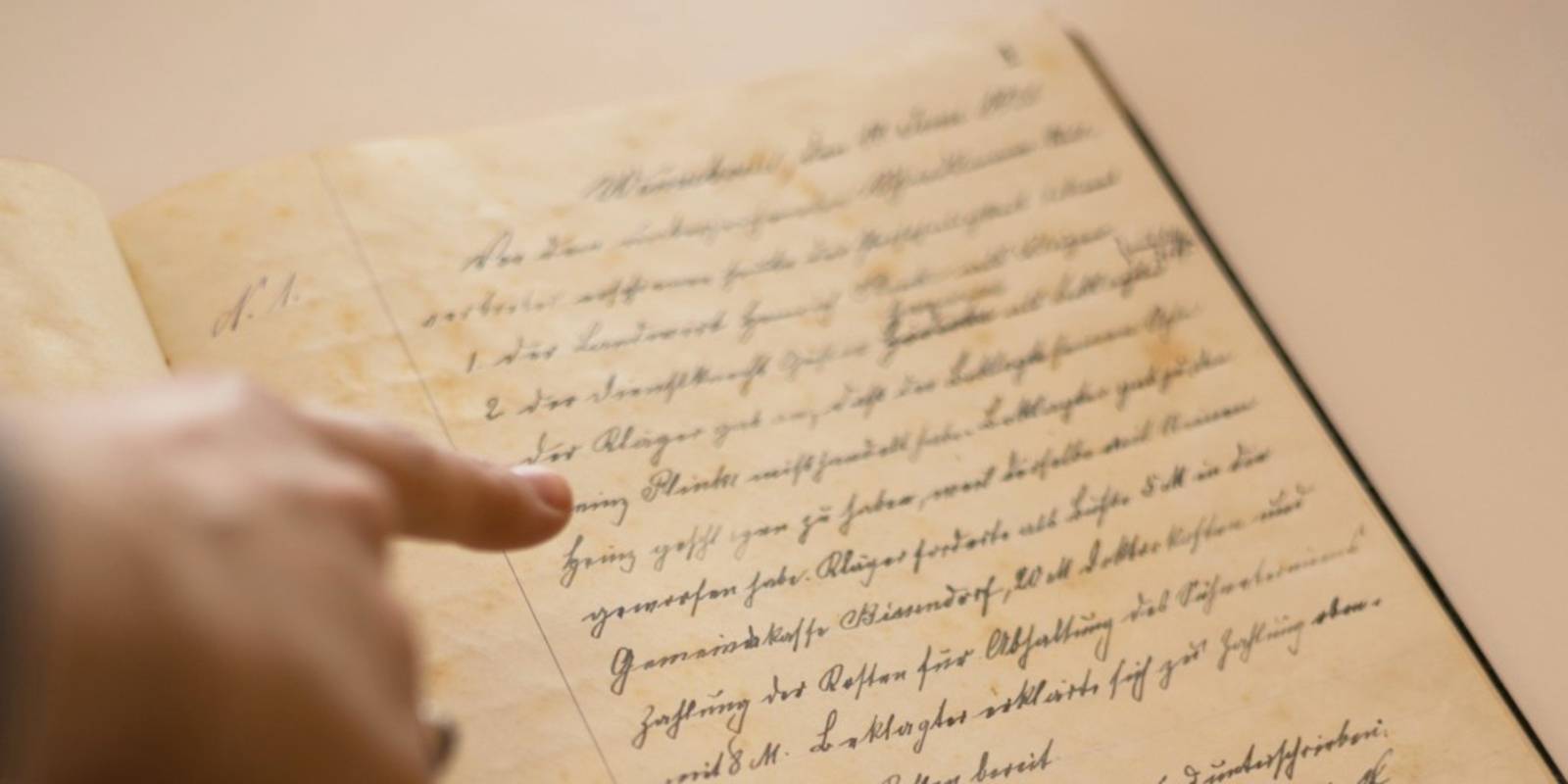 Eine Hand zeigt auf ein altes Dokument mit Handschrift.