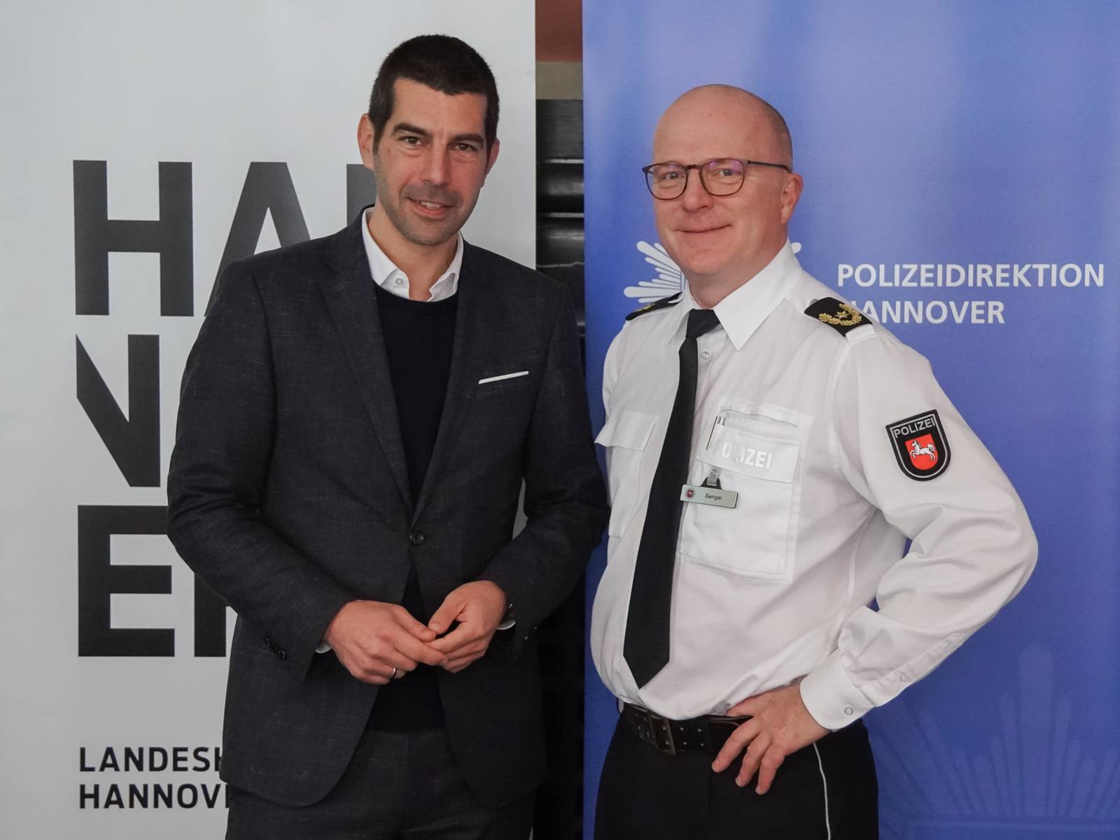 Zwei Männer vor Plakaten.