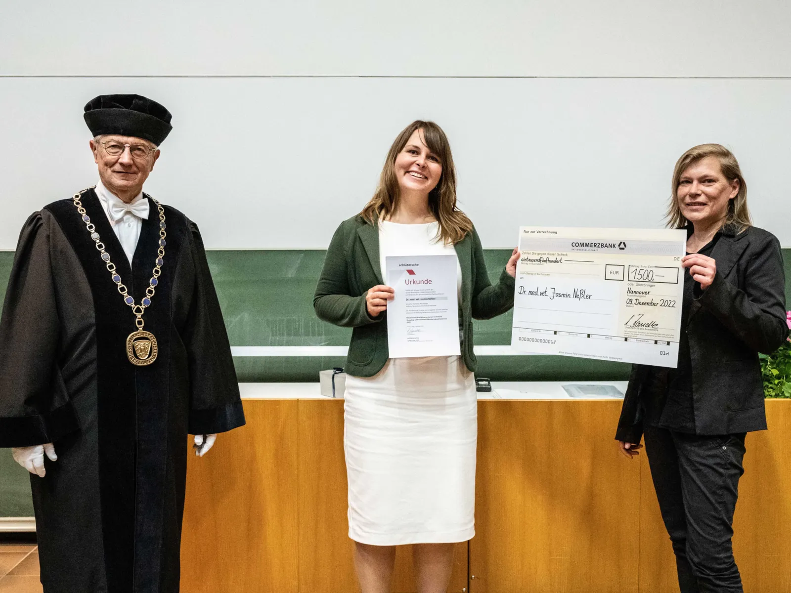 Zwei Frauen und ein Mann, die Frauen halten Urkunden in den H&auml;nden, der Mann tr&auml;gt ein festliches Ornat.