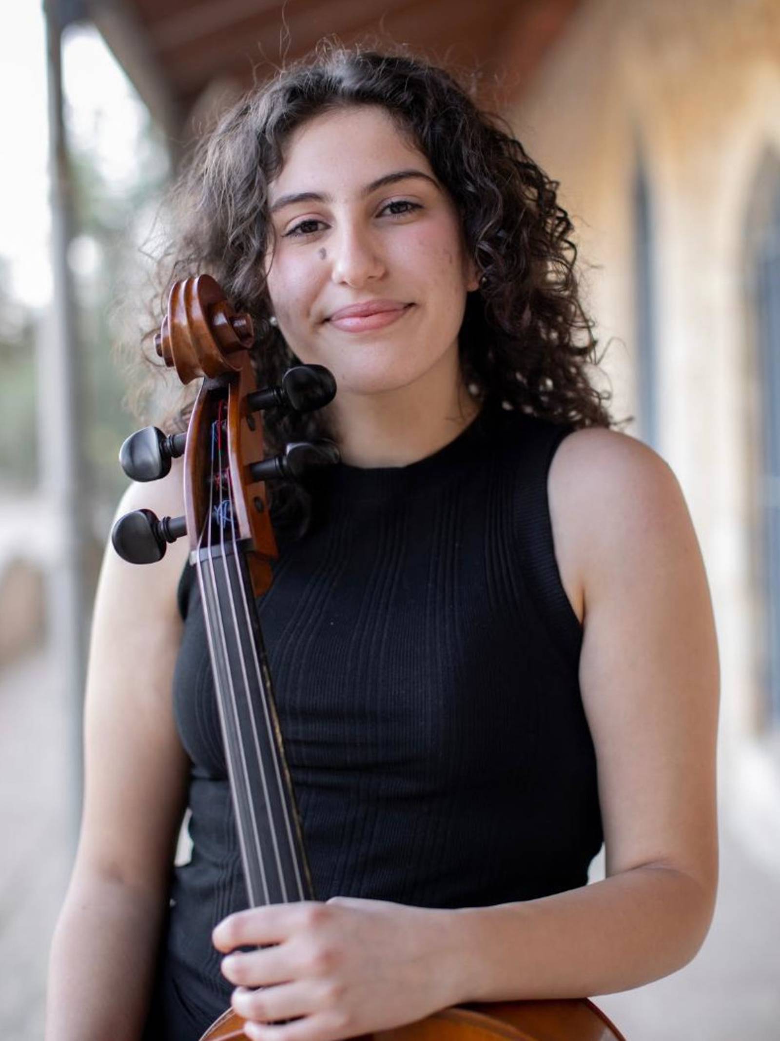 Porträtfoto einer Musikerin vor ihrem Cello.