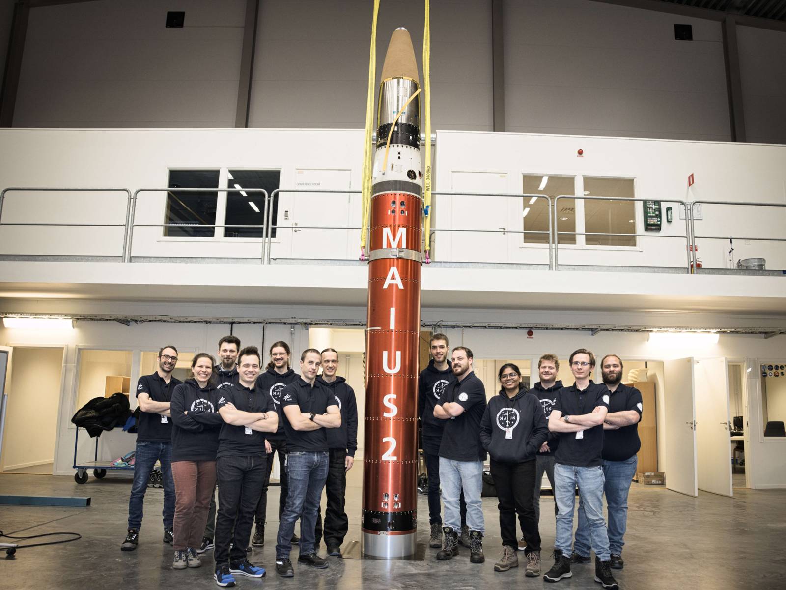 Menschen posieren neben einer Rakete mit der Aufschrift MAIUS 2.