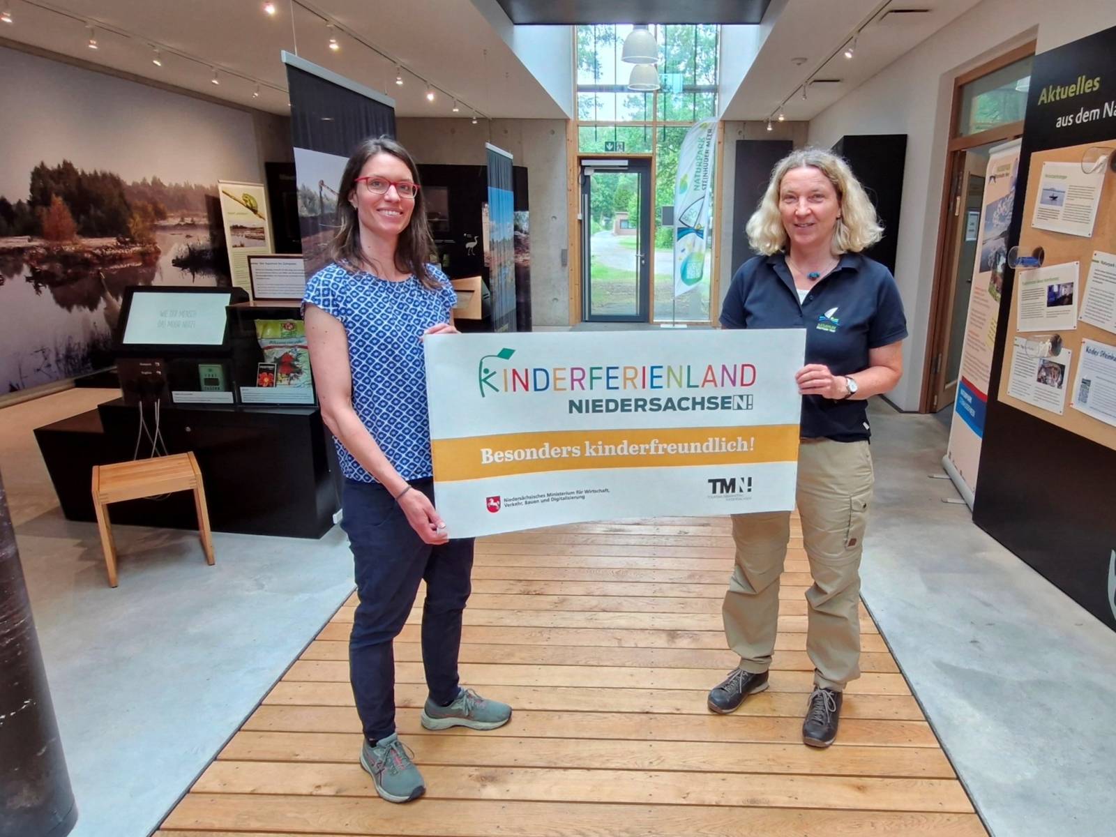 Zwei Personen halten ein Plakat: Kinderferienland Niedersachsen - Besonders Kinderfreundlich