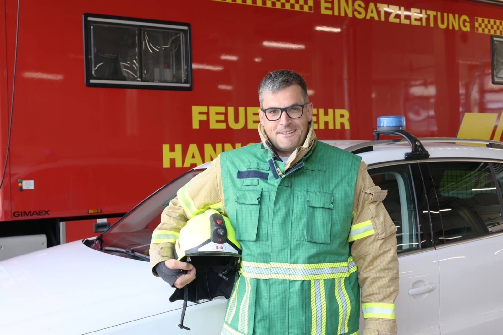 Pressesprecher mit grüner Weste vor dem Einsatzleitwagen 3-4