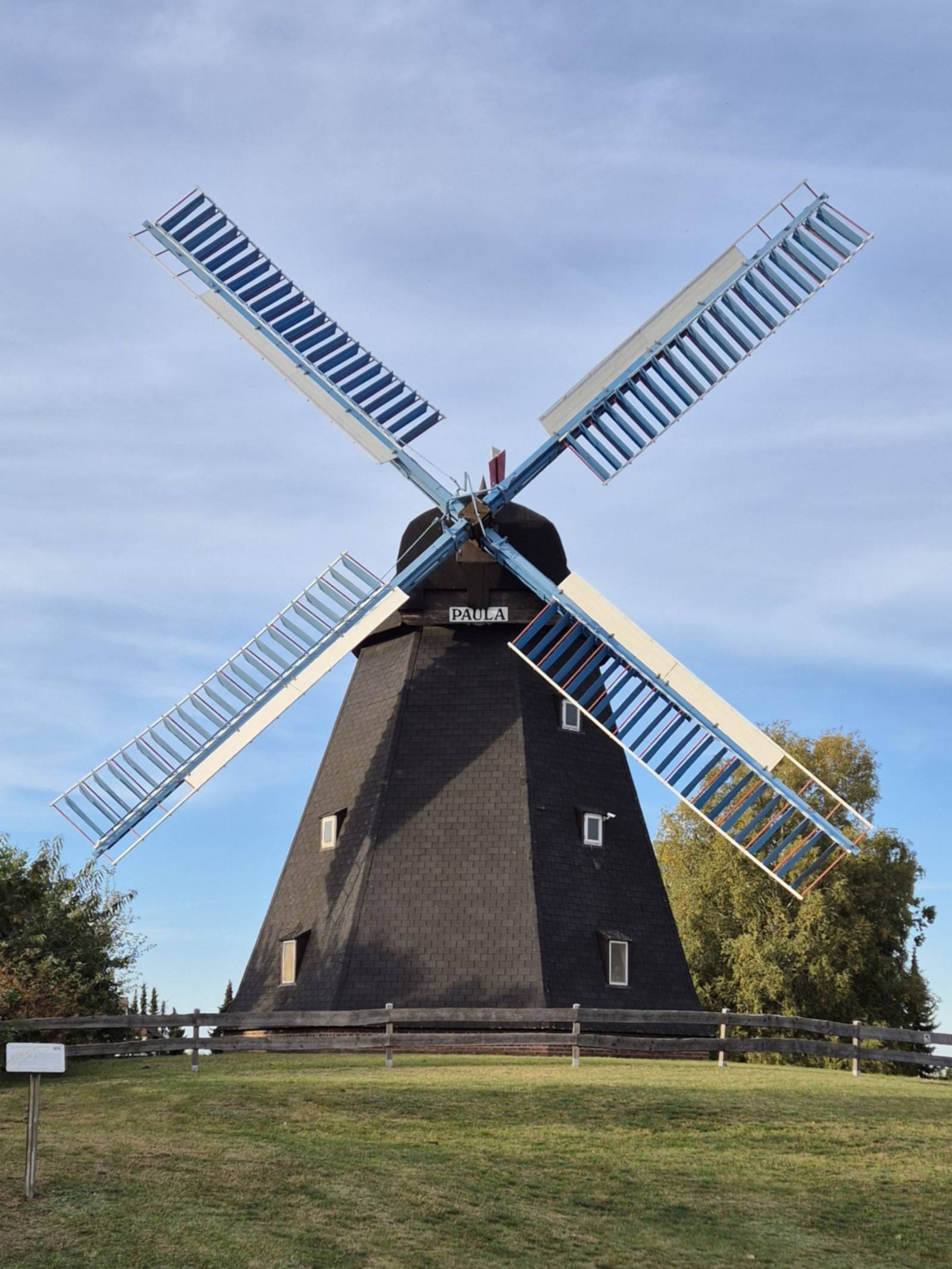 Auf einem Hügel steht eine Bockwindmühle