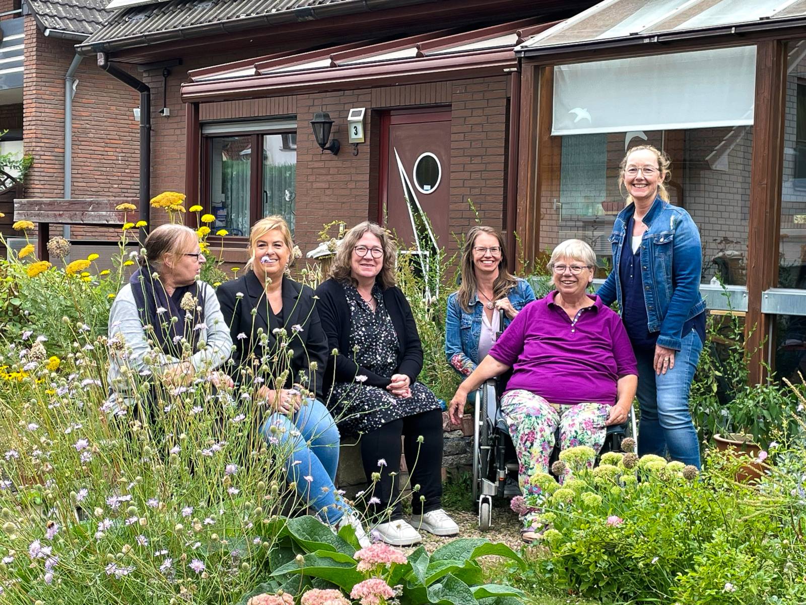 Sechs Frauen in einem Garten.