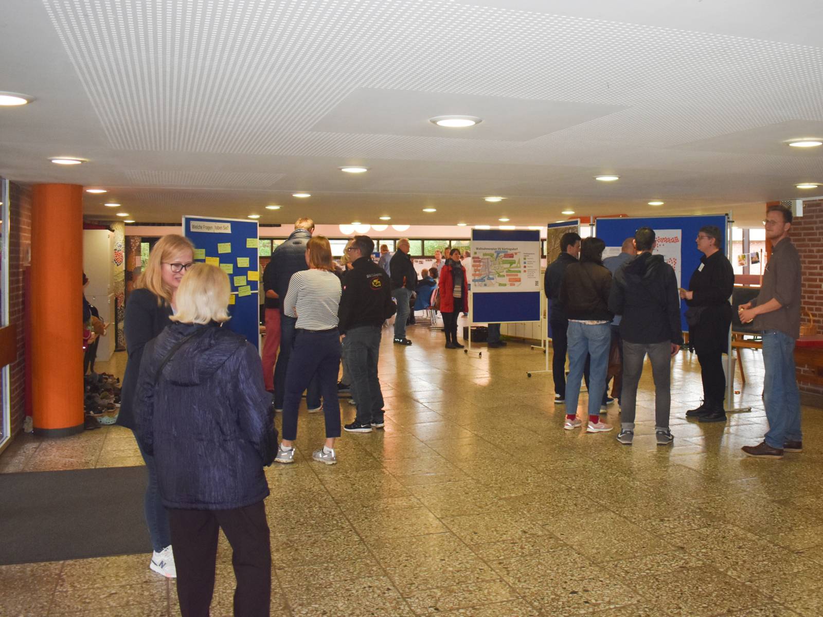 Eine Halle mit Menschen in Gespr&auml;chen und vor Info-Tafeln