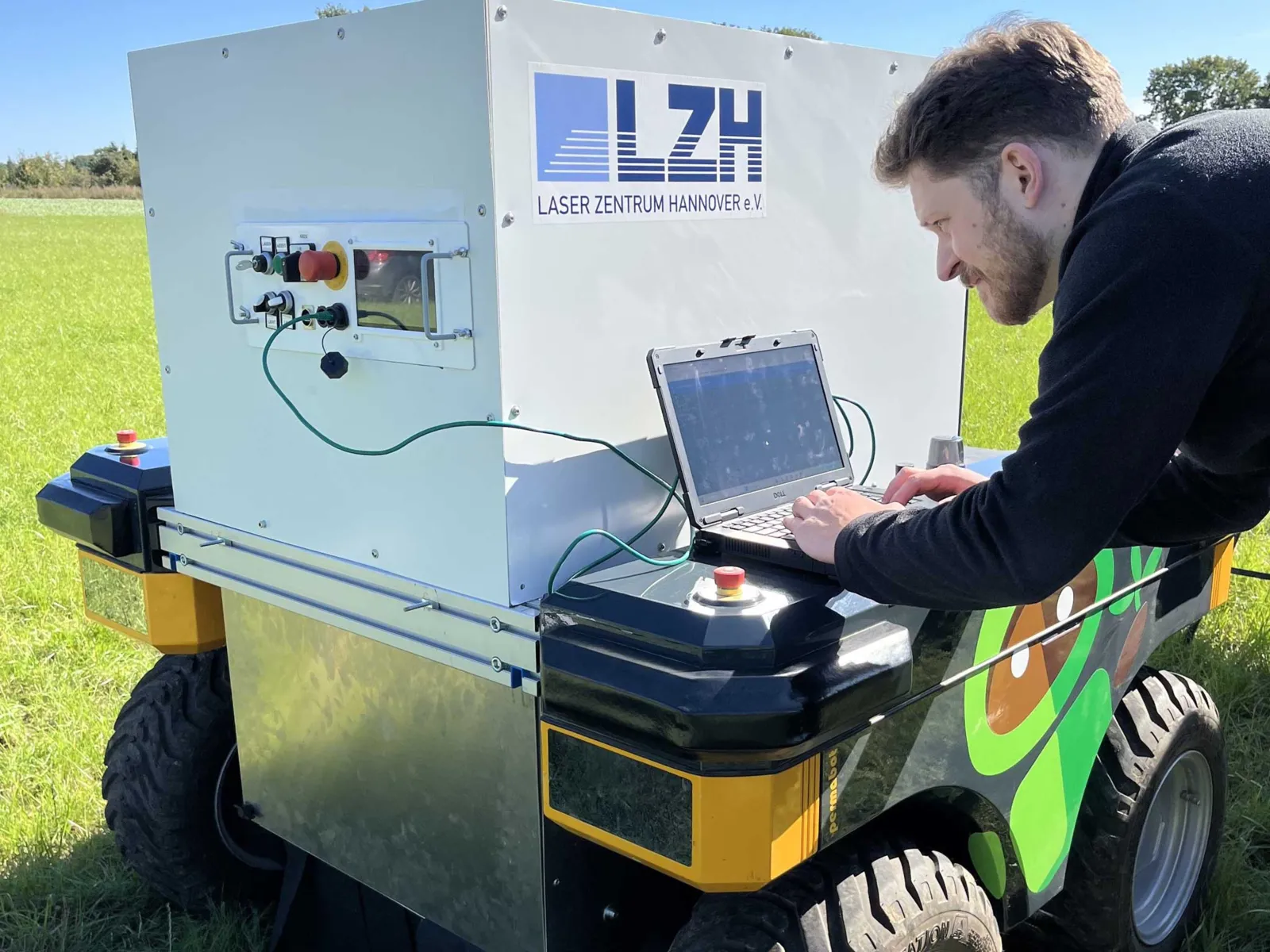 Mann an einem Laptop auf einem kleinen Wagen mit der Aufschrift "LZH Laserzentrum Hannover".