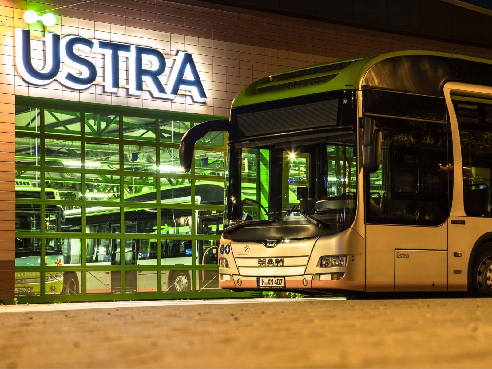 Ein MAN Bus bei Nacht auf dem Betriebshof Vahrenwald vor Bushalle mit dem beleuchteten ÜSTRA-Logo.
