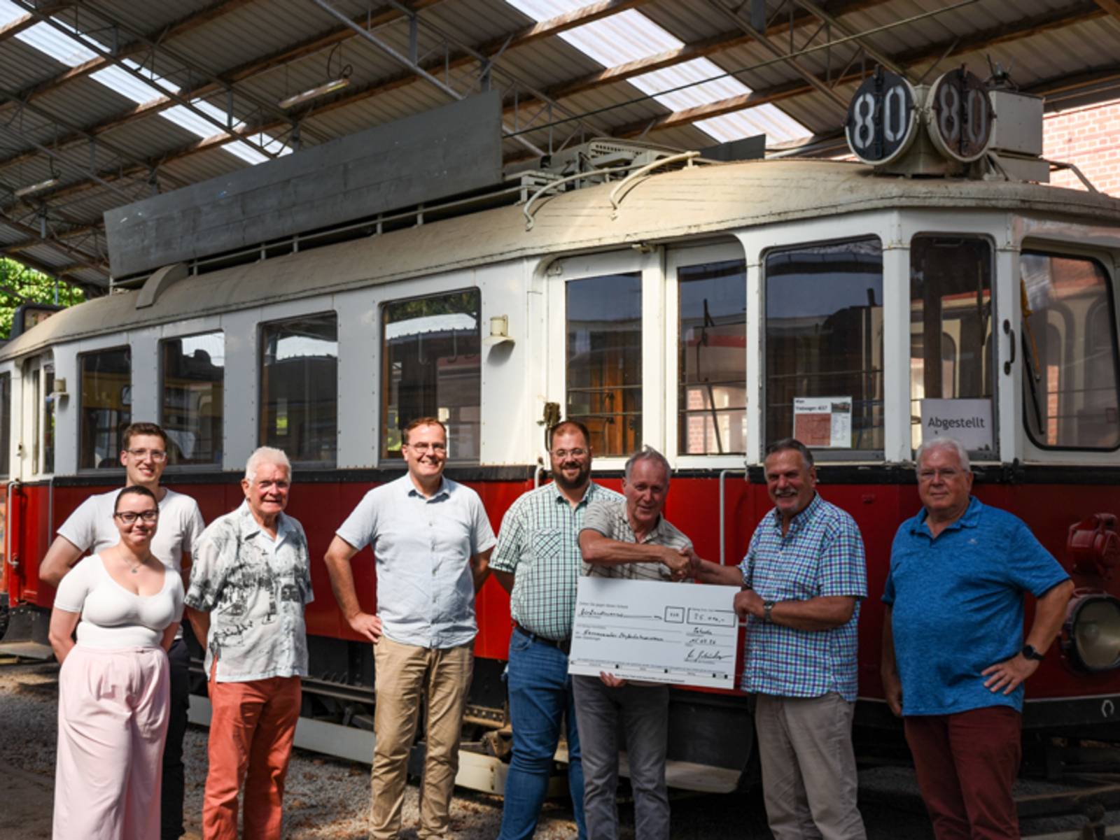 Checkübergabe vor einer historischen Straßenbahn