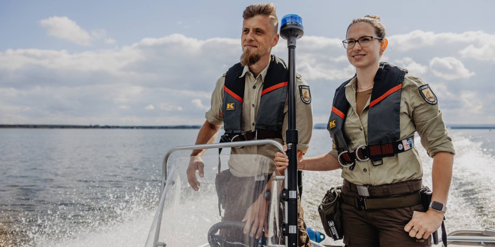 Eine Rangerin und ein Ranger fahren mit einem Boot.