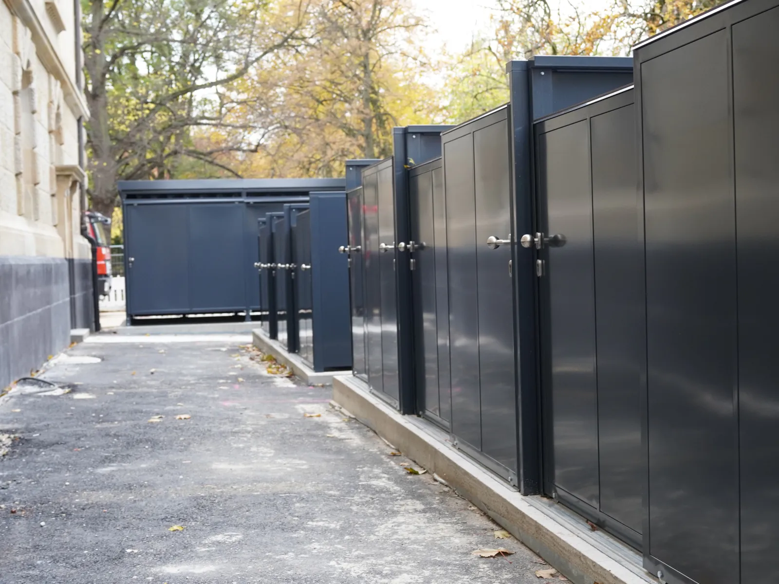 Links eine Geb&auml;udewand, rechts schwarze Metallt&uuml;ren, dazwischen ein Gang.