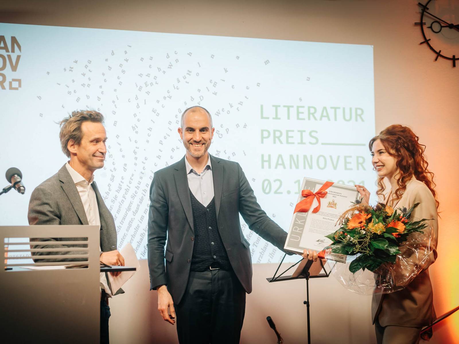 Drei Personen auf einer Bühne.