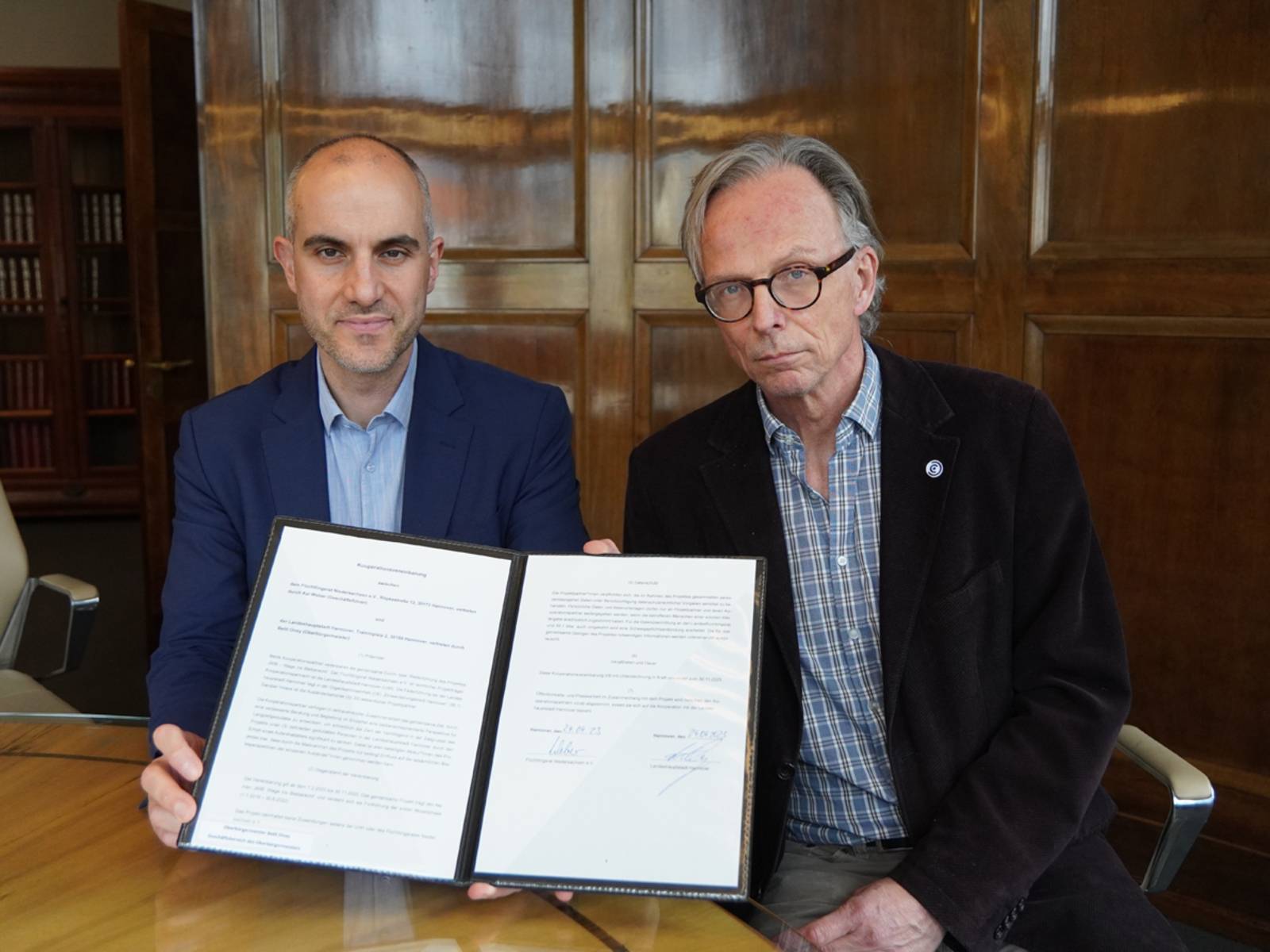 Oberbürgermeister Belit Onay (links) mit Kai Weber, Geschäftsführer des Flüchtlingsrat Niedersachsen (rechts), bei der Unterzeichnung der Kooperationsvereinbarung.