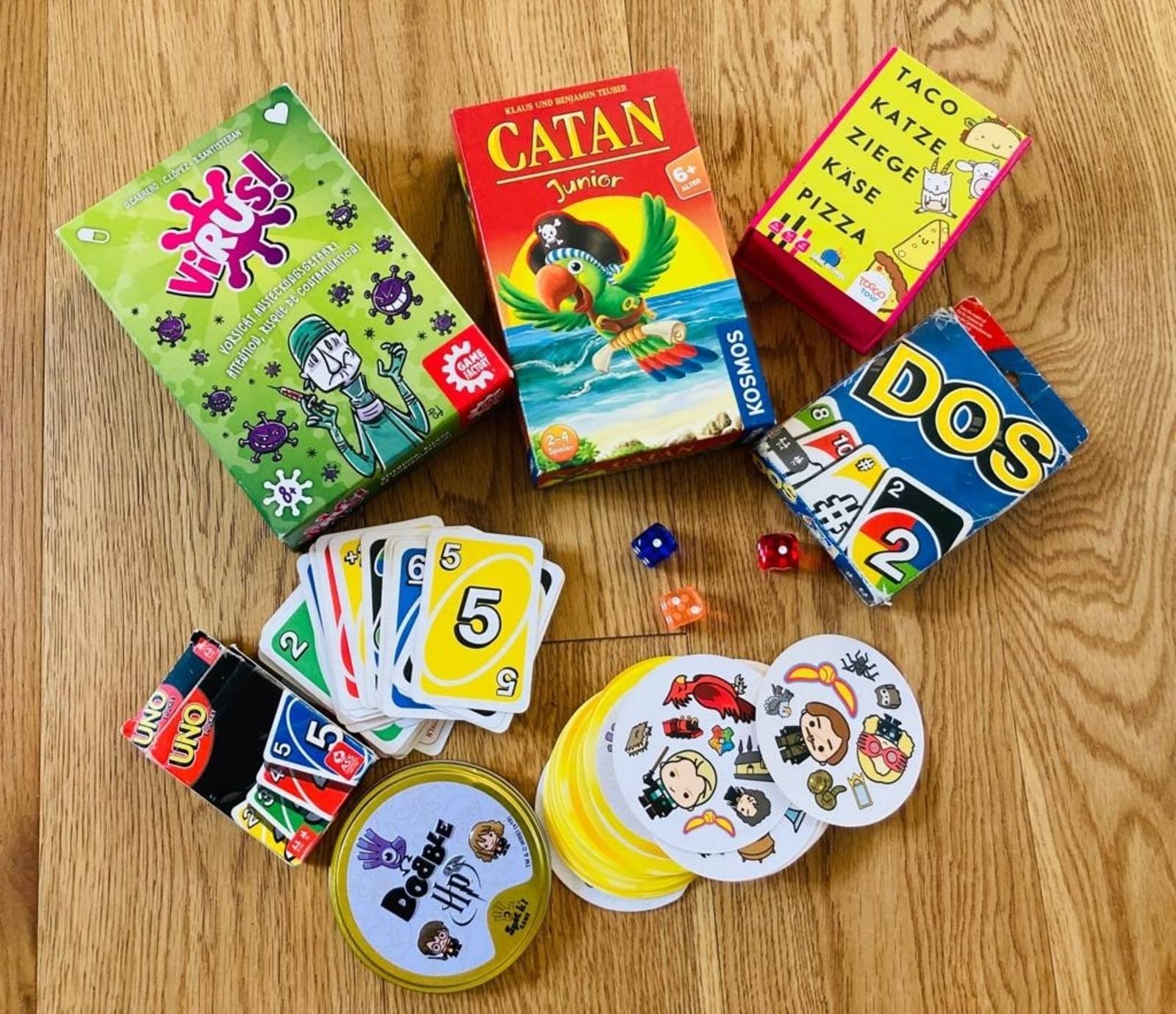 Zu sehen sind mehrere Karten- und Brettspiele. Darunter "Dobble" und "Uno". Außerdem sind ein paar Karten aufgefächert daneben.