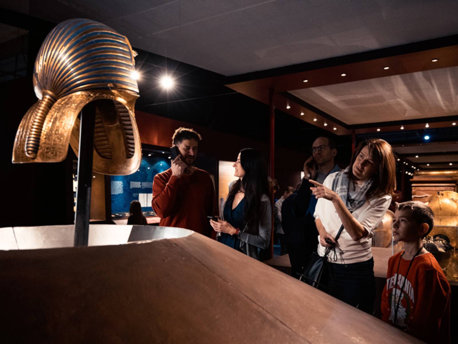 F&uuml;nf Personen verschiedenen Alters stehen vor einer &auml;gyptischen Totenmaske