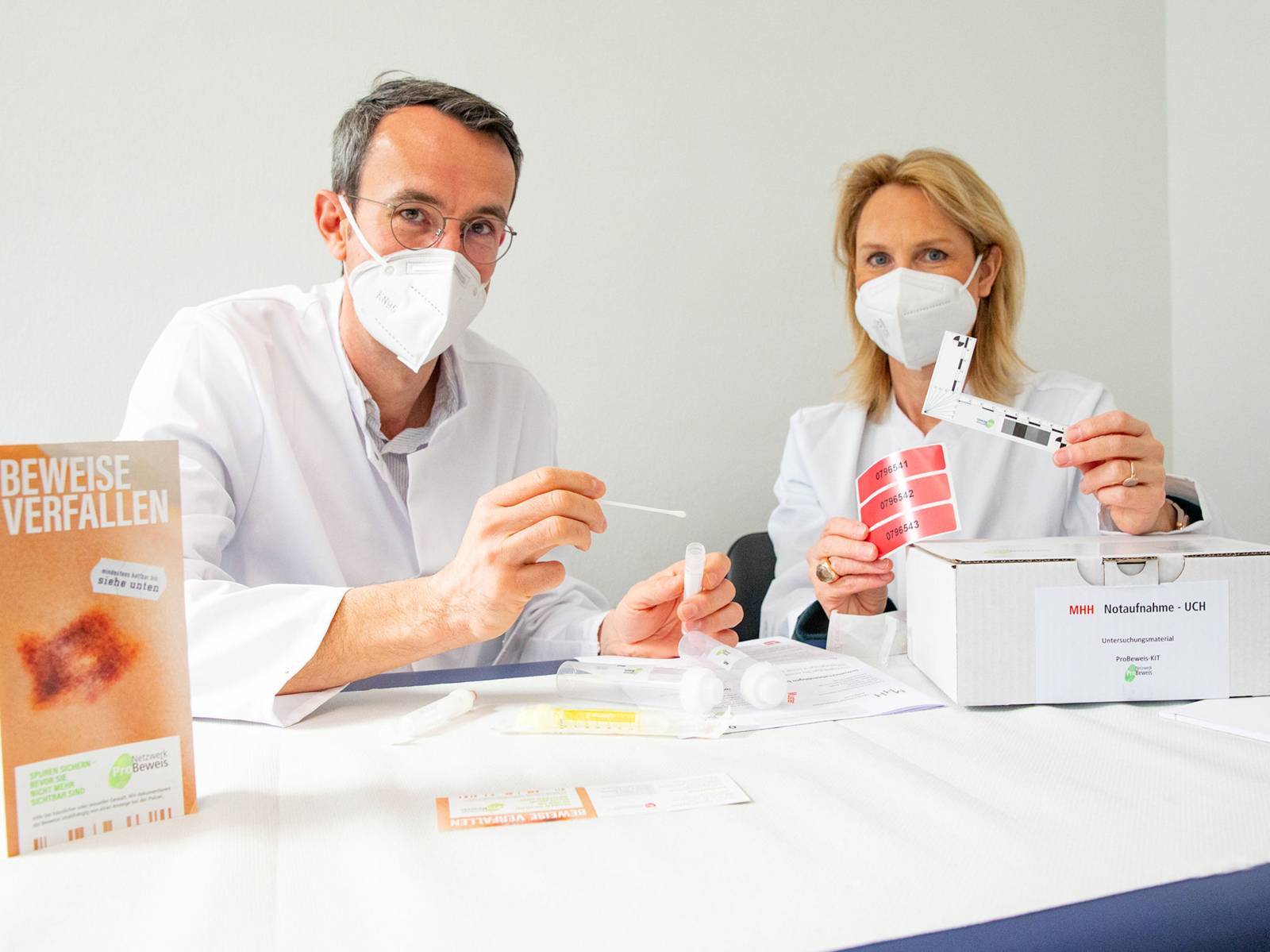 Eine Frau und ein Mann mit Nasen-Mundschutz-Masken in weißen Kitteln