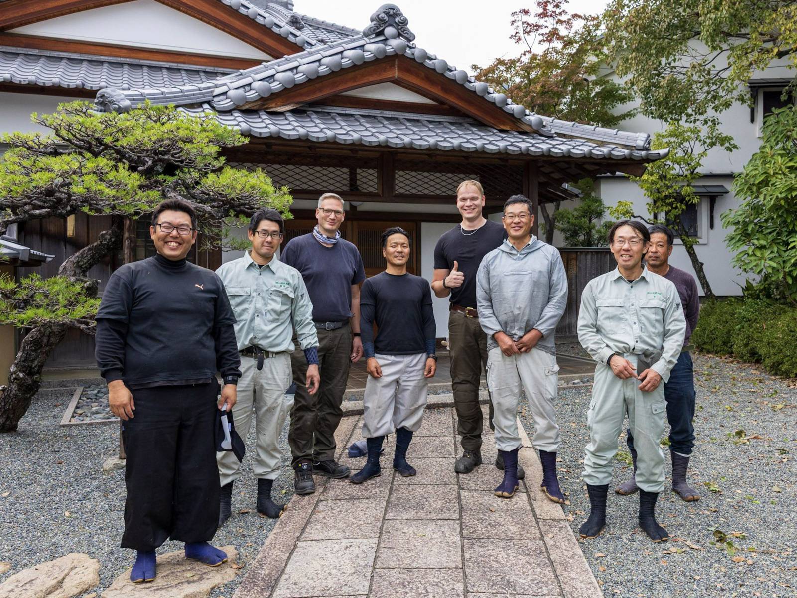Acht Personen vor einem Tee-Haus.
