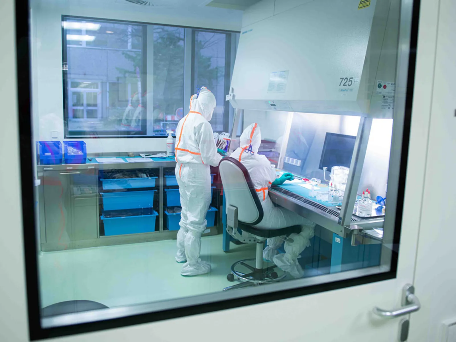 Menschen in medizinischen Schutzanzügen in einem Labor.