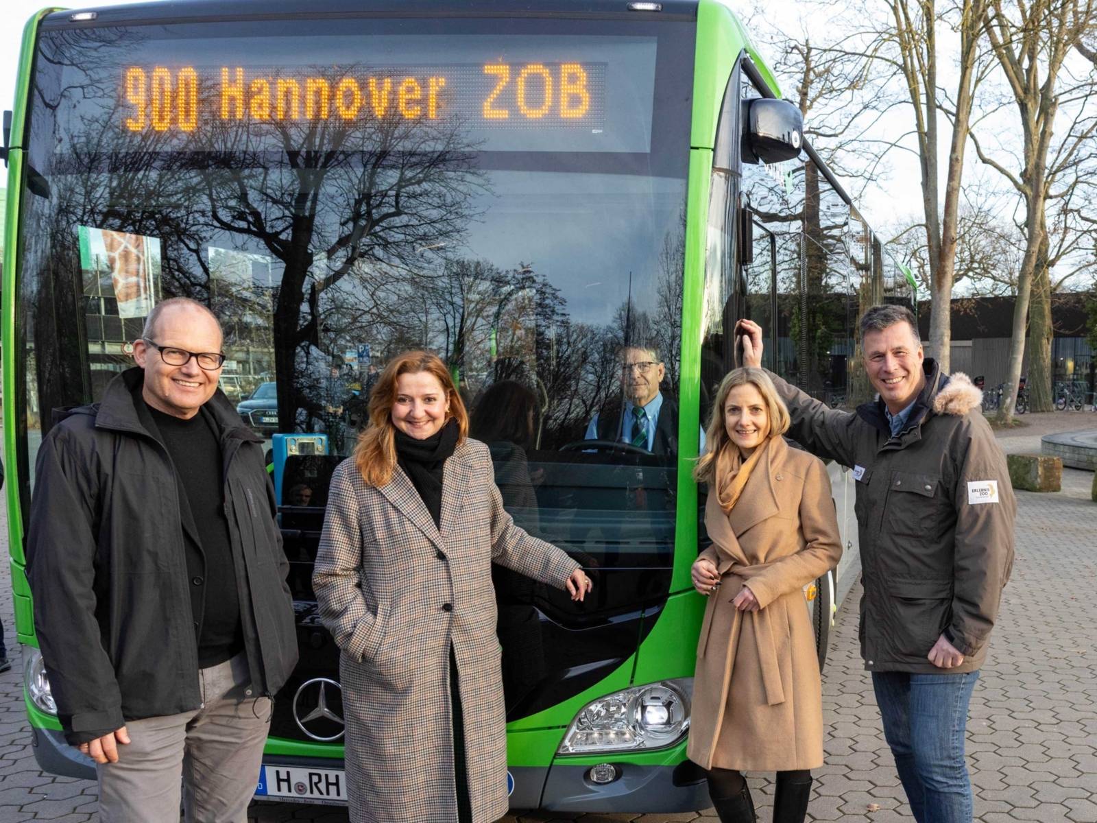 Zwei Frauen und zwei Männer stehen vor einem Bus der Linie 900