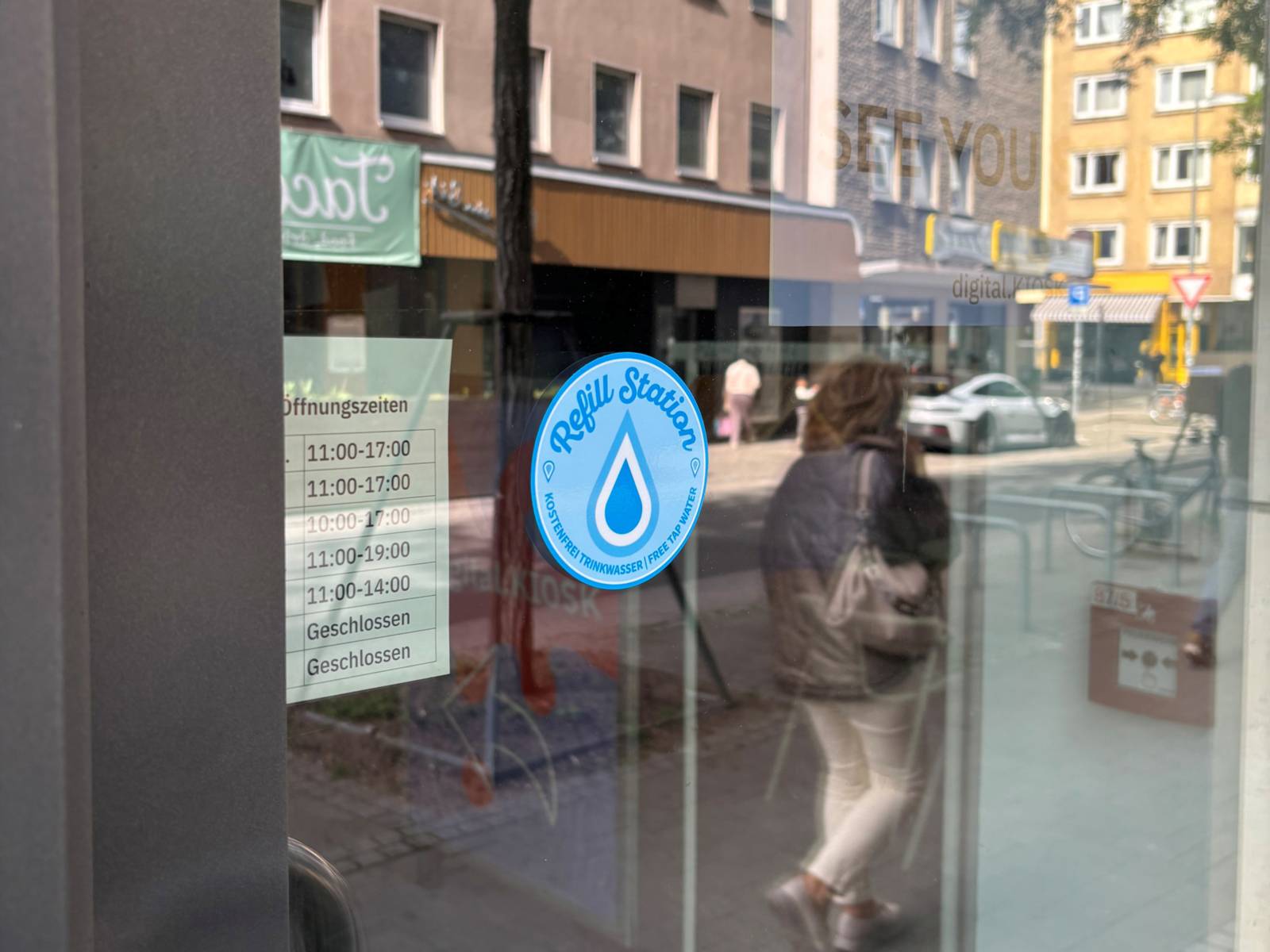 Ein Aufkleber mit einem blauen Tropfen darauf. Er klebt an einer Scheibe.